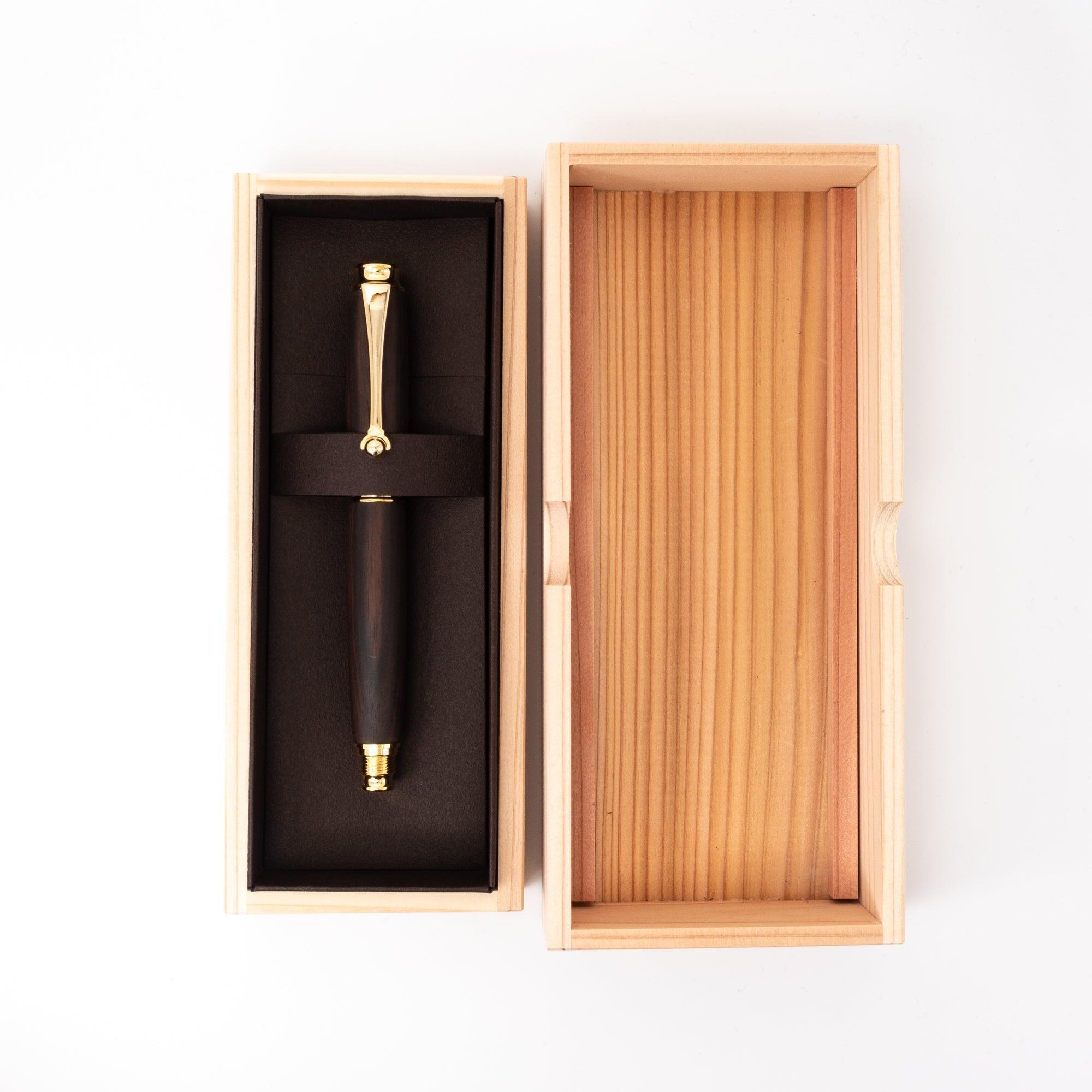 A Japanese ebony wood fountain pen with gold accents elegantly displayed in an open wooden box with black lining, highlighting its luxurious presentation.