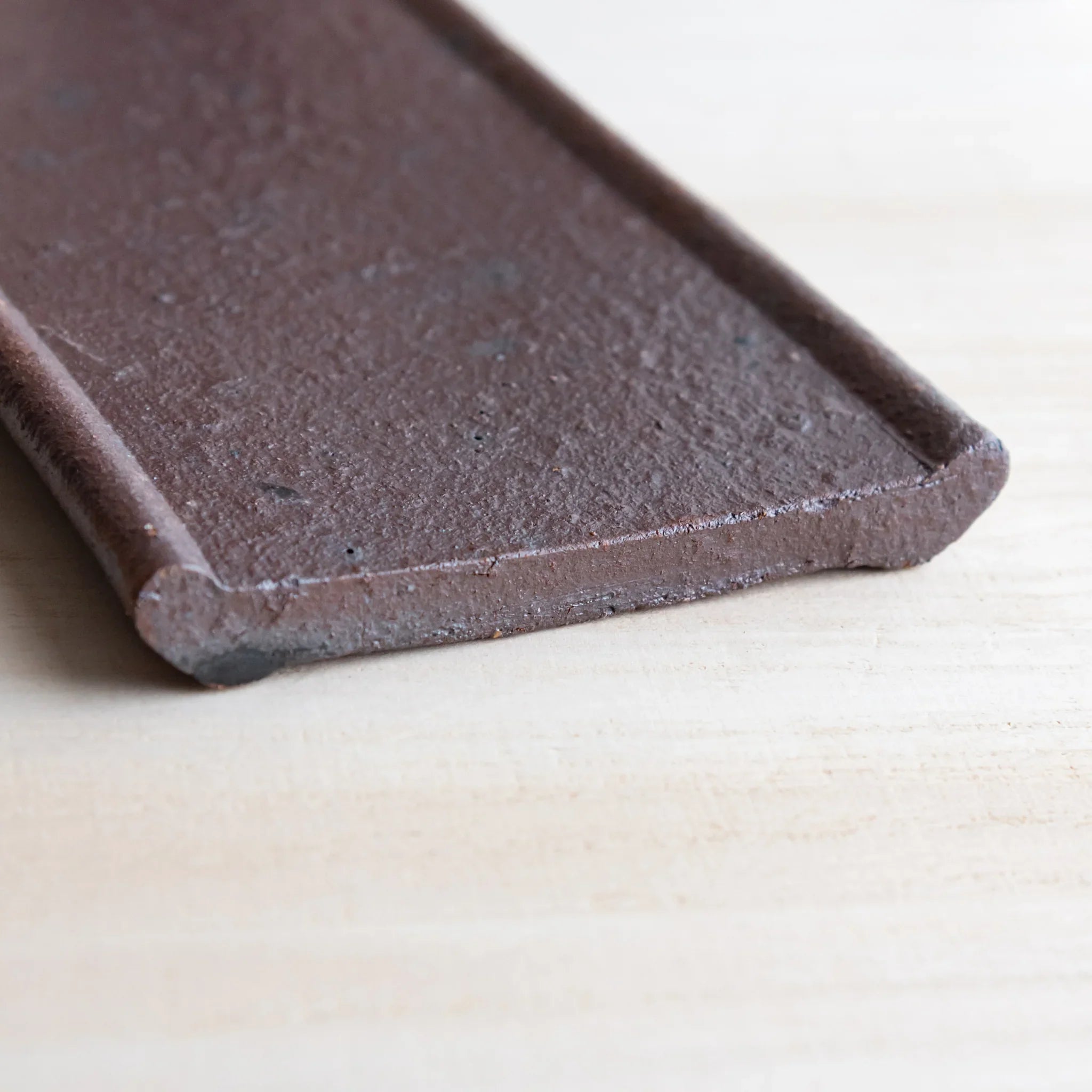 Japanese Pen Tray Desk Accessory top view of red ceramic tray showing grooves and raised edges on light wooden surface.
