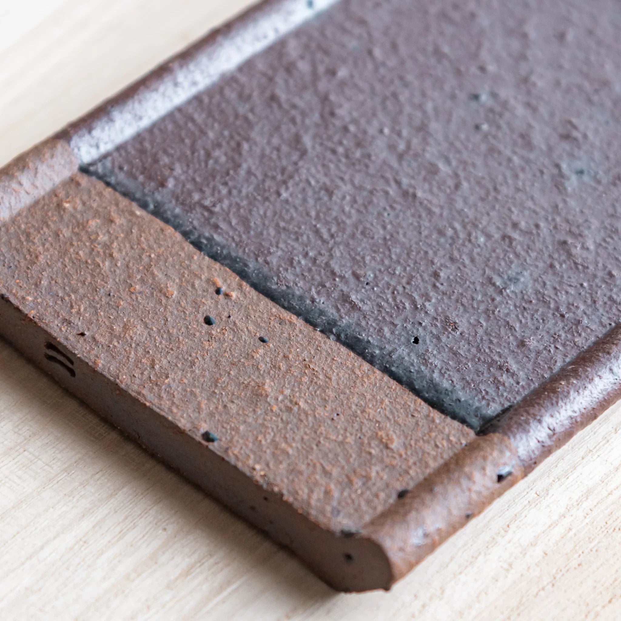Japanese Pen Tray Desk Accessory close-up view of red ceramic tray with brown edge on wooden surface.