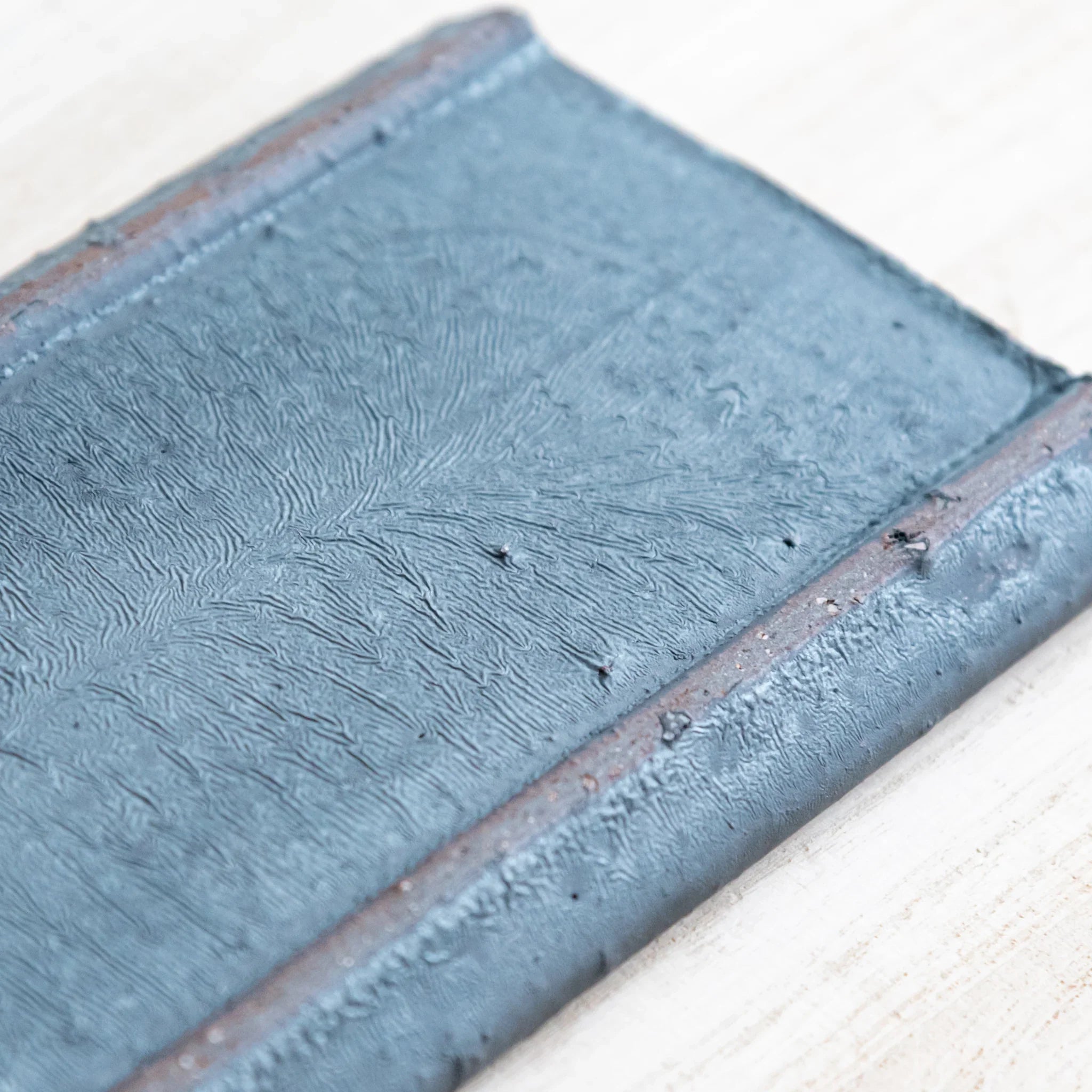 Japanese Pen Tray Desk Accessory close-up texture view of silver gray ceramic tray surface with brown edges on wood.