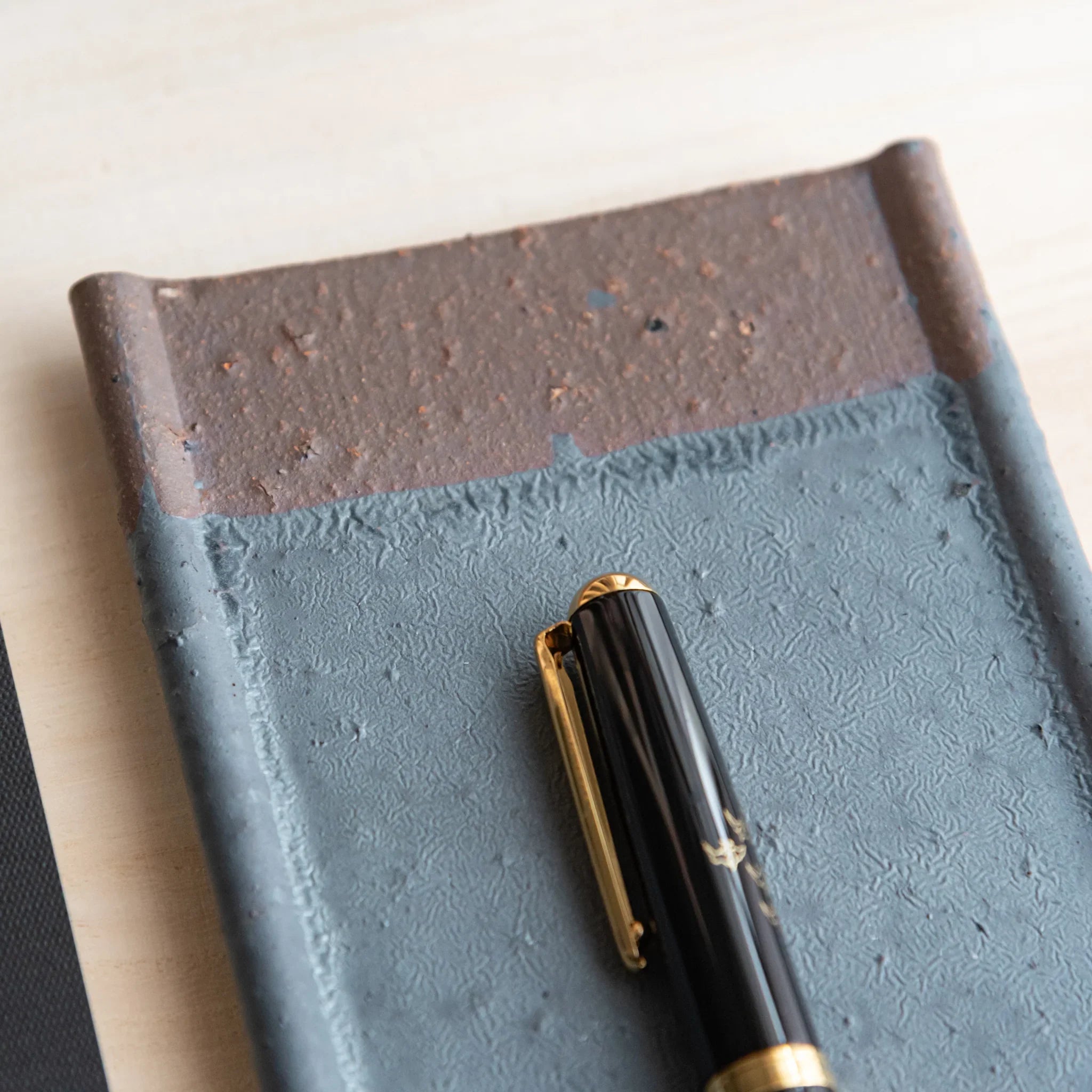 Japanese Pen Tray Desk Accessory close-up of silver-gray ceramic tray with fountain pen resting vertically at rim.