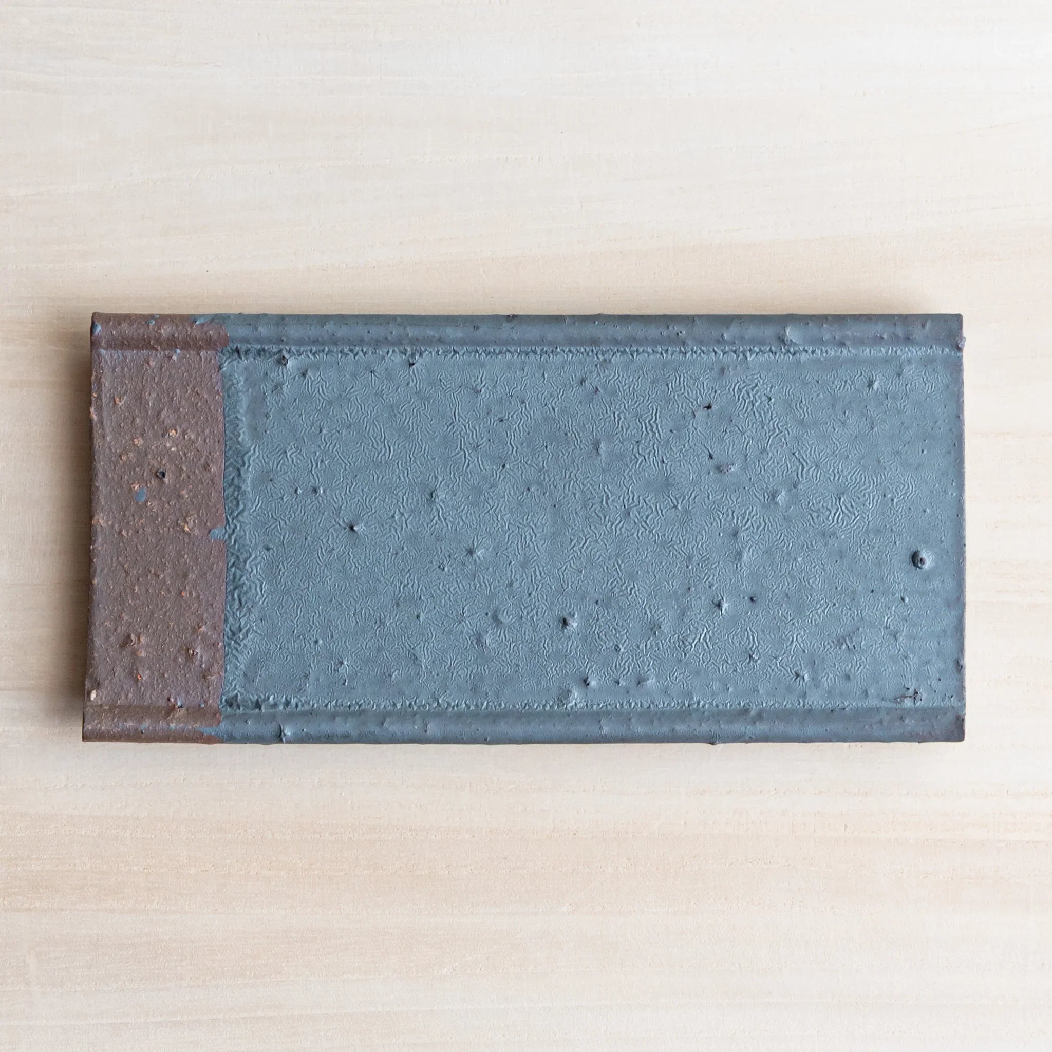 Japanese Pen Tray Desk Accessory top view of silver gray ceramic tray with brown edge on light wooden surface.