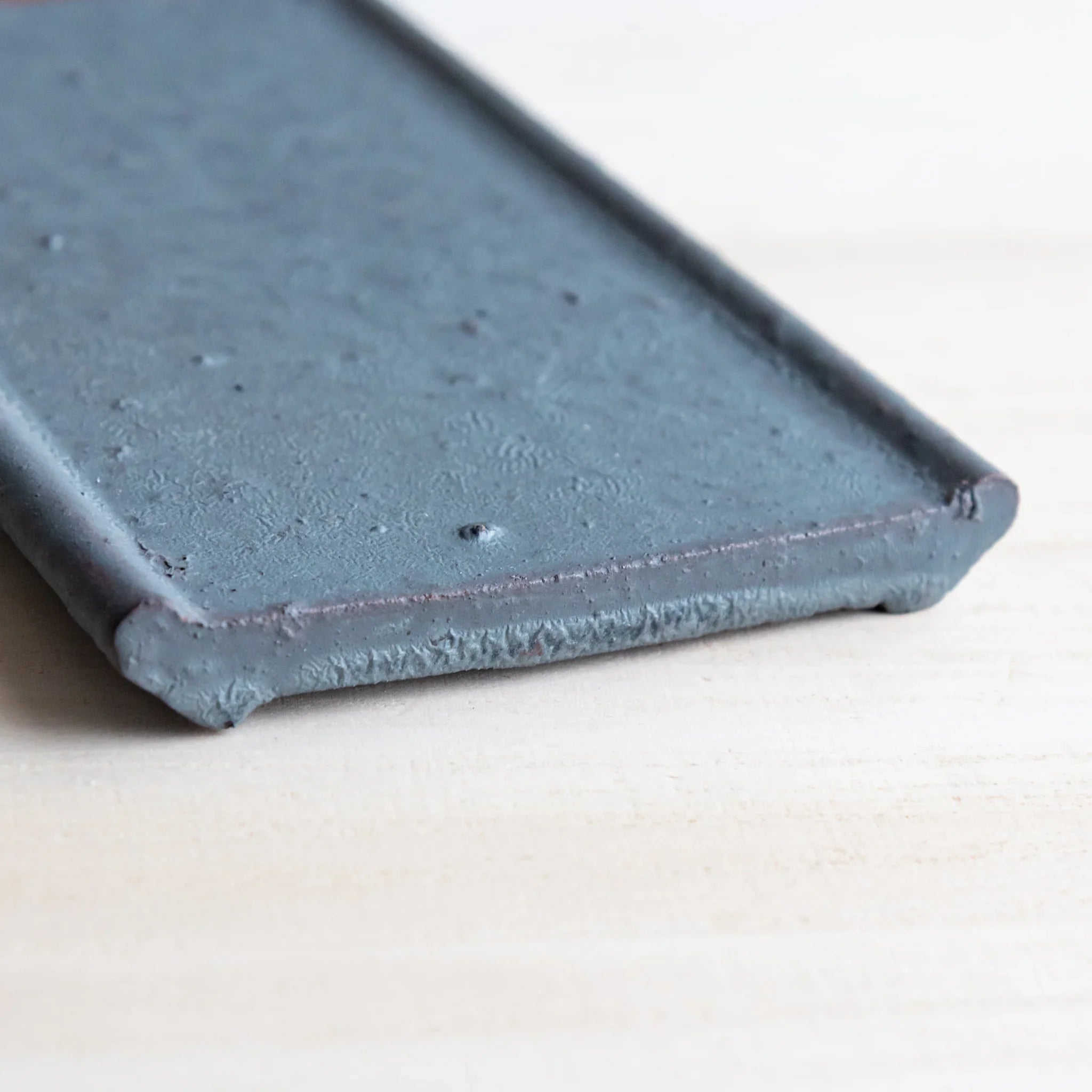 Japanese Pen Tray Desk Accessory angled corner view of silver gray ceramic tray on light wooden surface.