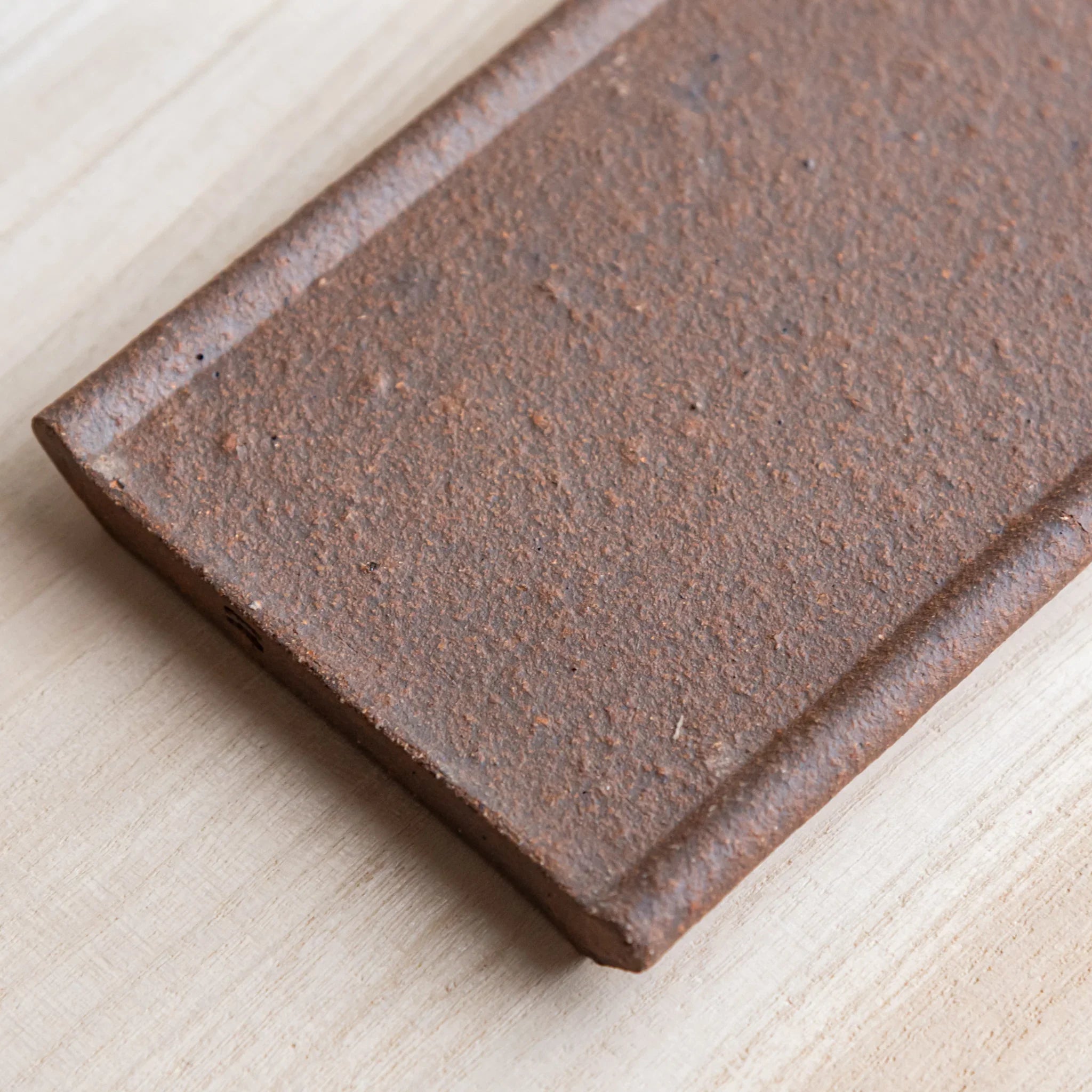 Japanese Pen Tray Desk Accessory close-up angled view of yakishime clay  ceramic tray on wooden desk.
