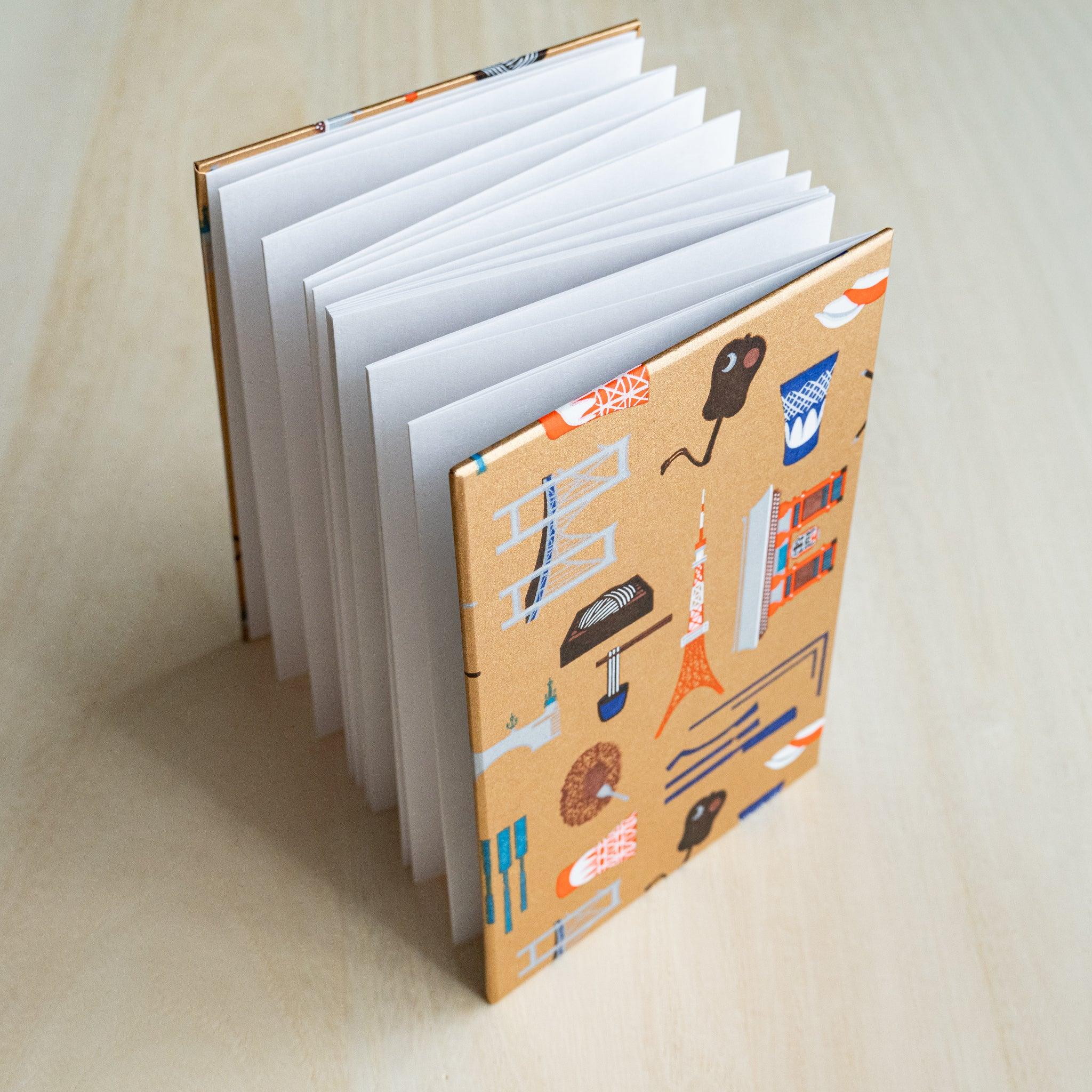 Edo Tokyo goshuincho stamp book standing open, accordion-fold white pages fanned out, gold patterned cover
