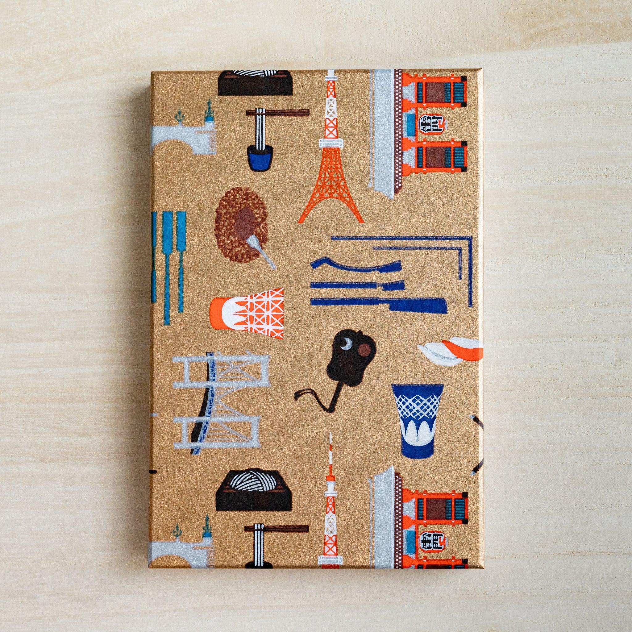 Full gold cover of Edo Tokyo goshuincho stamp book, printed with Tokyo Tower, Skytree, bridges and sushi motifs