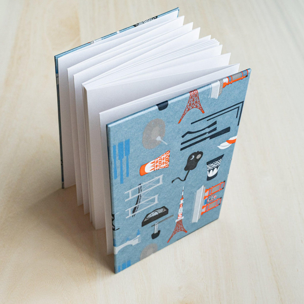 Edo Tokyo goshuincho stamp book standing open, accordion-fold white pages fanned out, slate blue cover