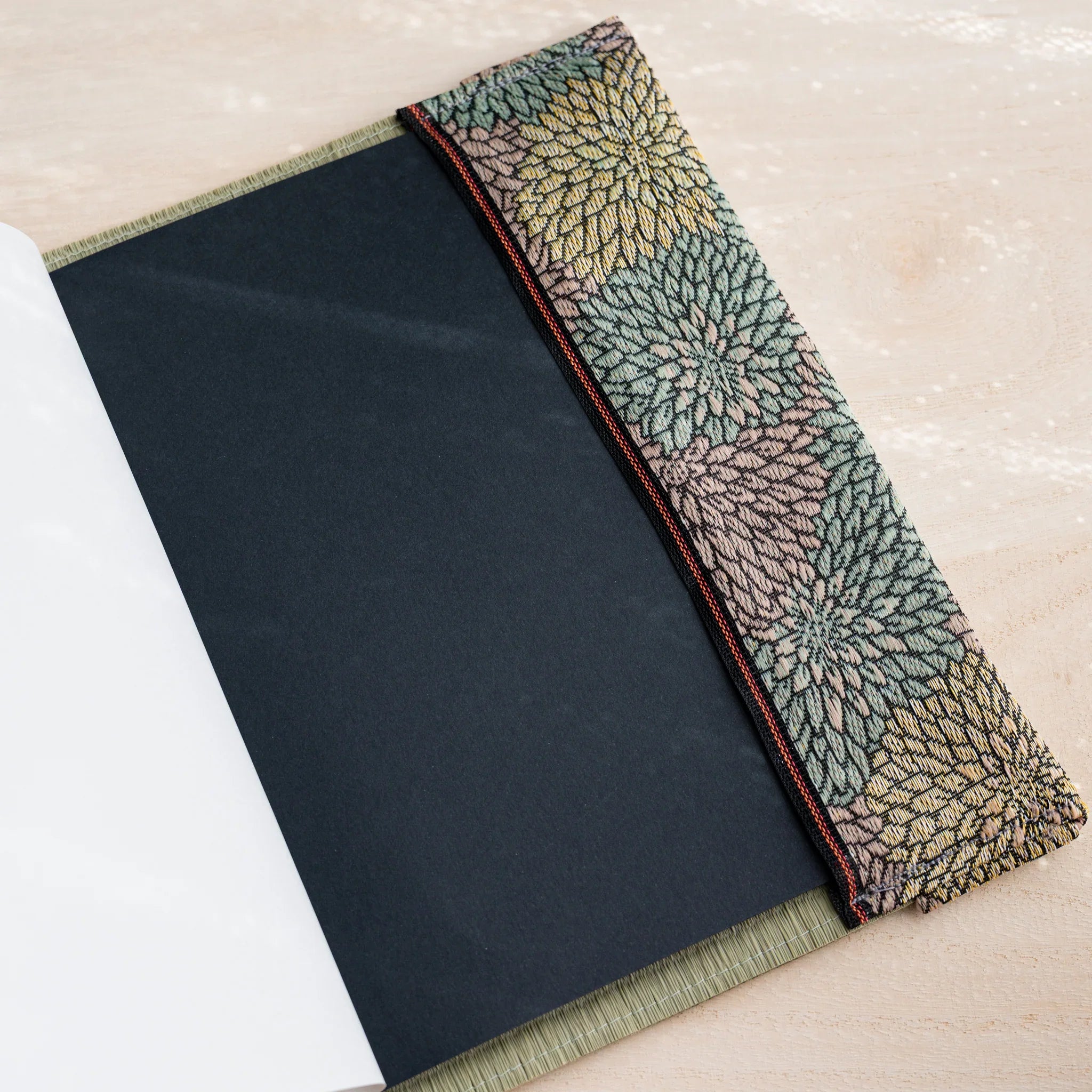 Tatami book cover inner flap open showing a black notebook cover and chrysanthemum patterned fabric band
