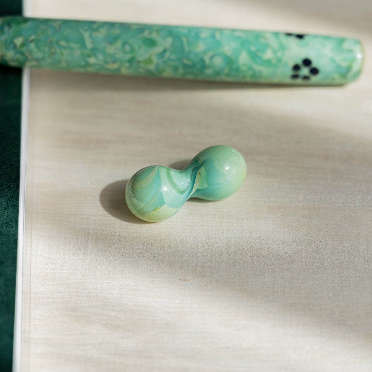 Two-sphere green marbled glass pen rest with the Emerald Flower pen barrel behind it