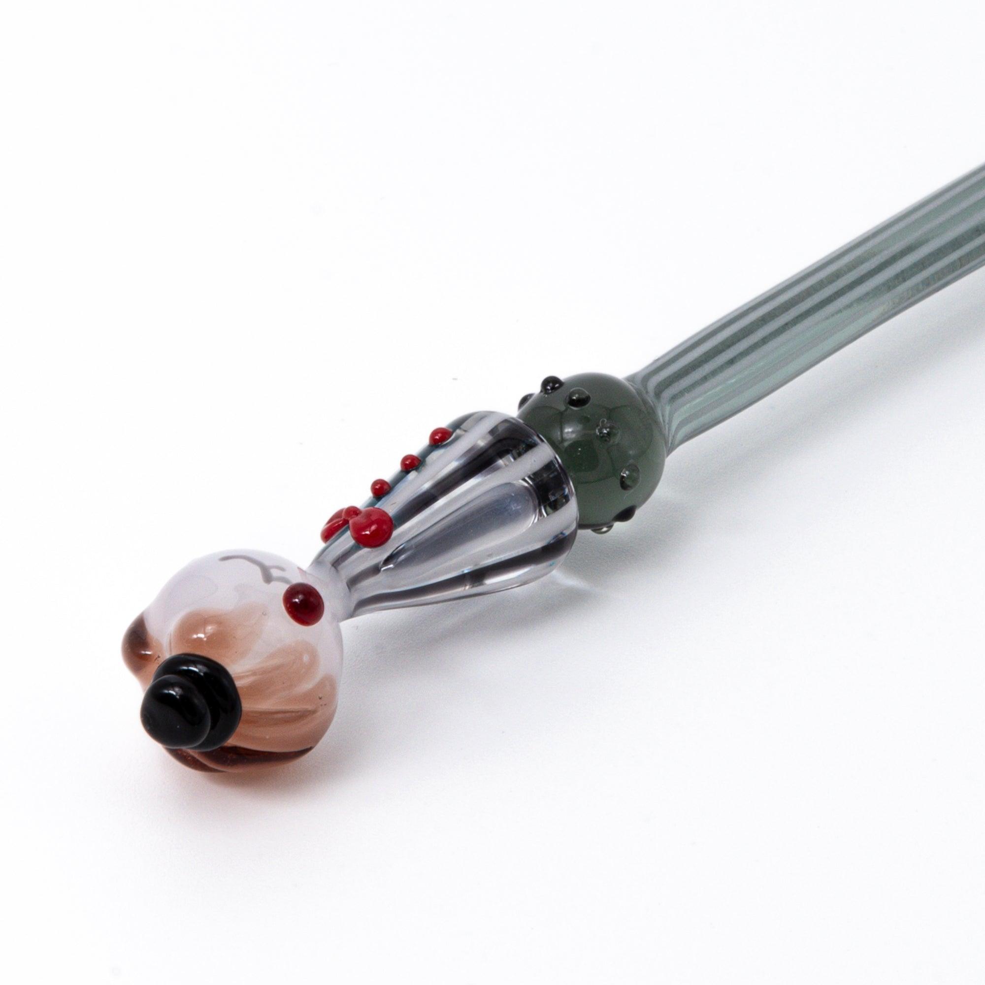 A striped glass dip pen with a whimsical lady figurine top, featuring elegant curves and handcrafted details.