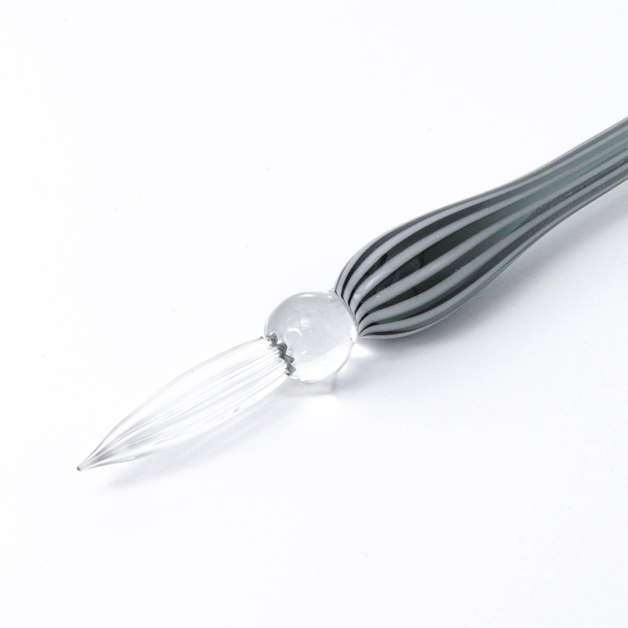 A striped glass dip pen with a whimsical lady figurine top, featuring elegant curves and handcrafted details.