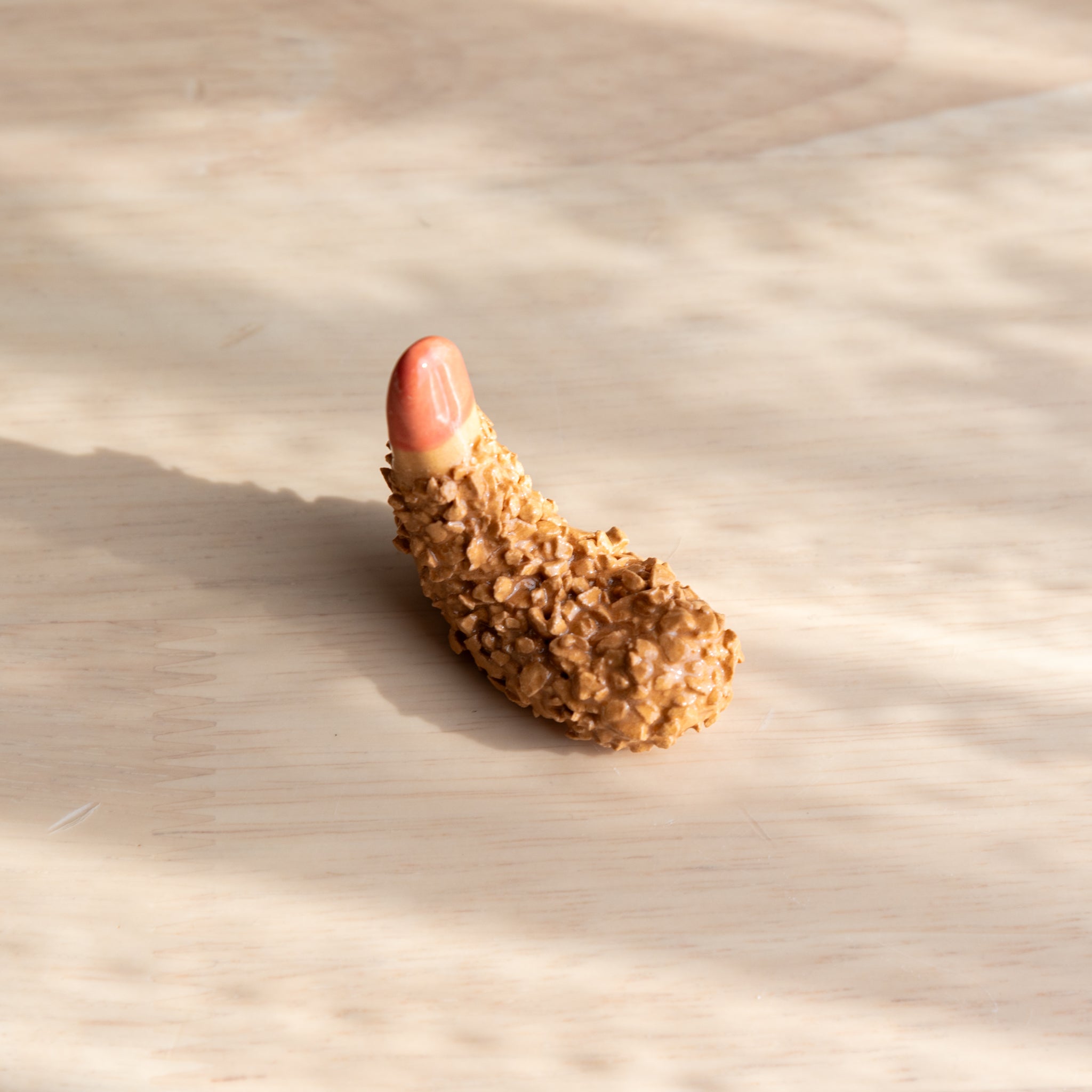 A handmade ceramic pen rest shaped as a fried shrimp, showcasing a playful and unique design in traditional Japanese stationery.