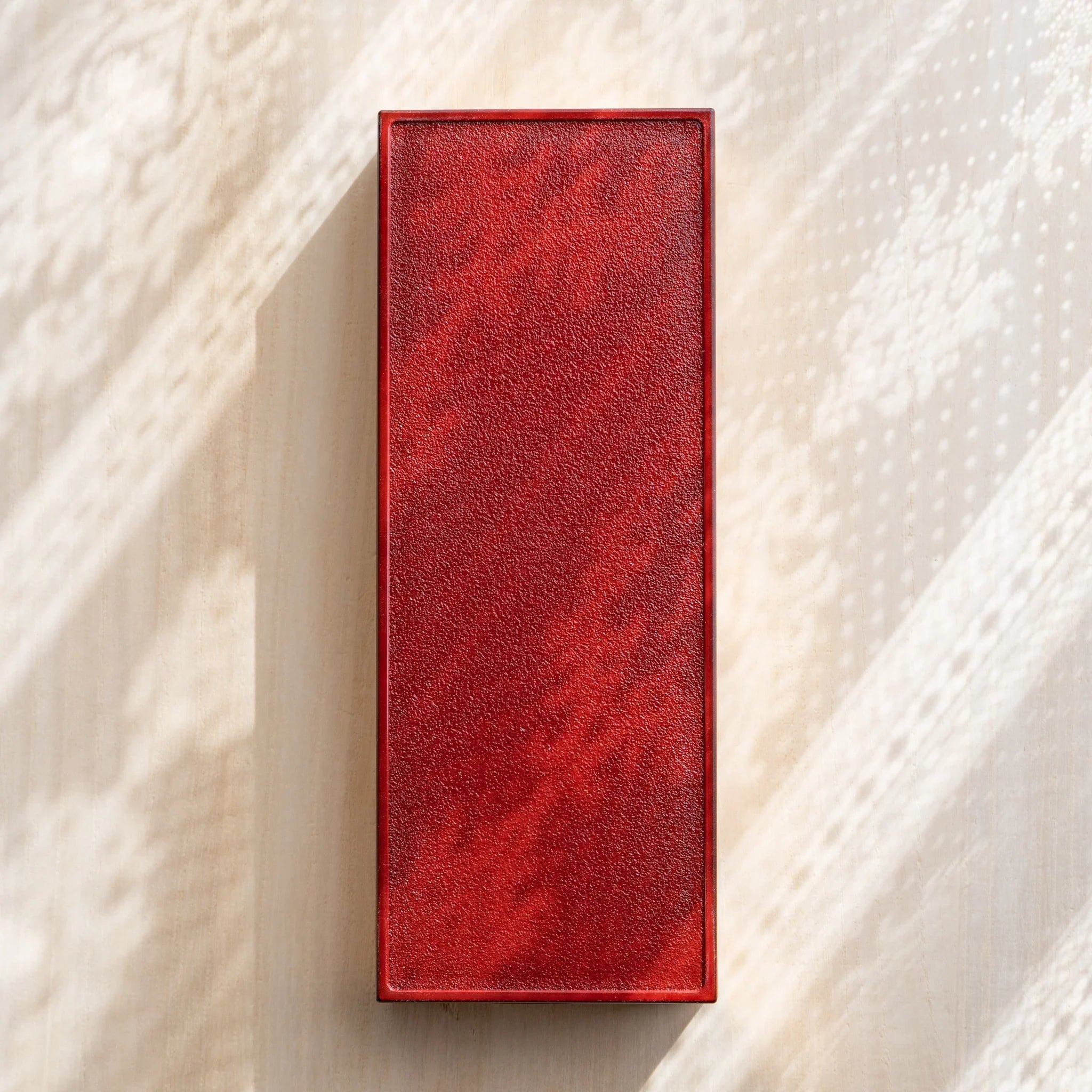 Bottom view of a Japanese pen case showing plain vermilion underside with simple, unadorned base