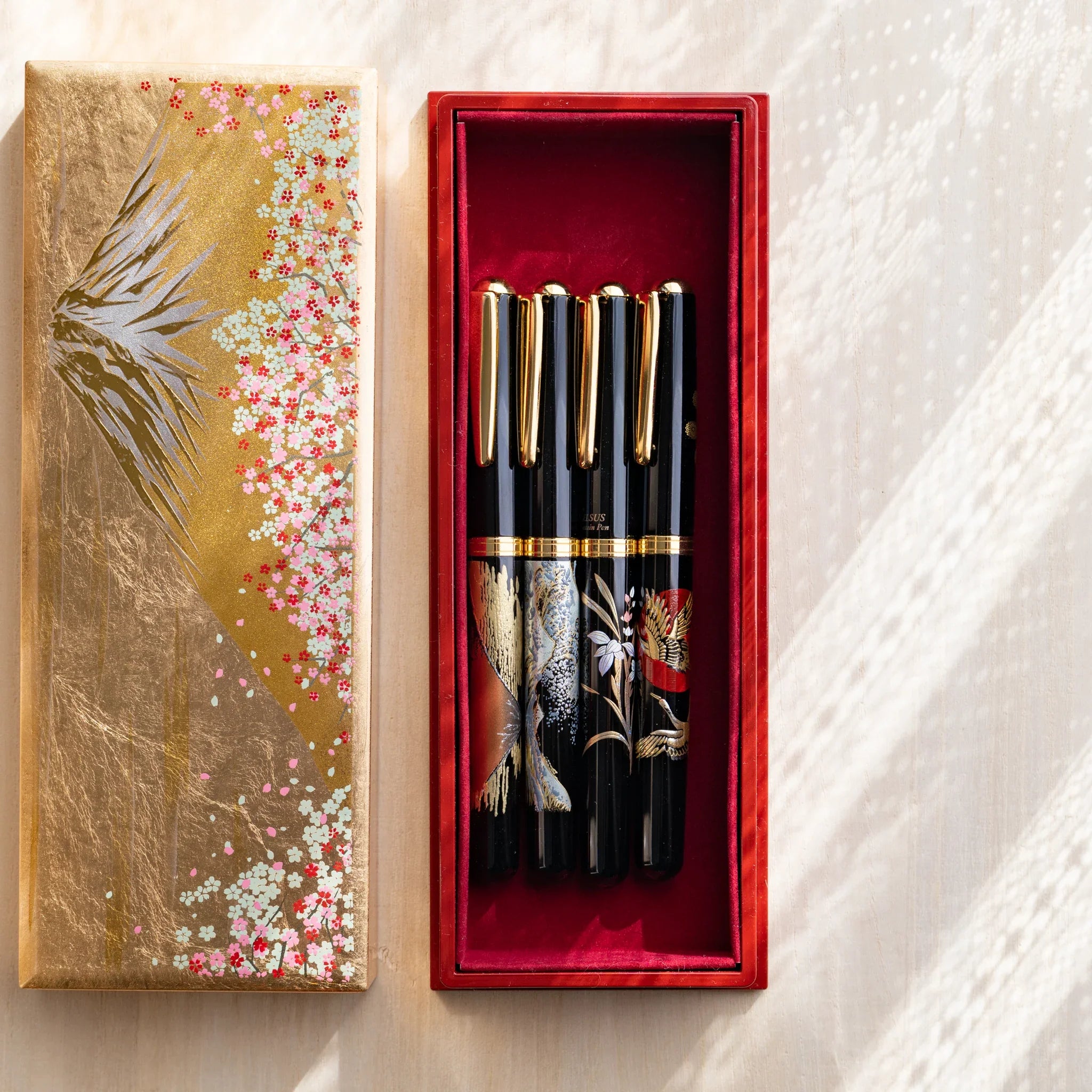 Handcrafted Japanese pen case with golden cherry blossom lid holding 4 lacquer pens in red velvet interior