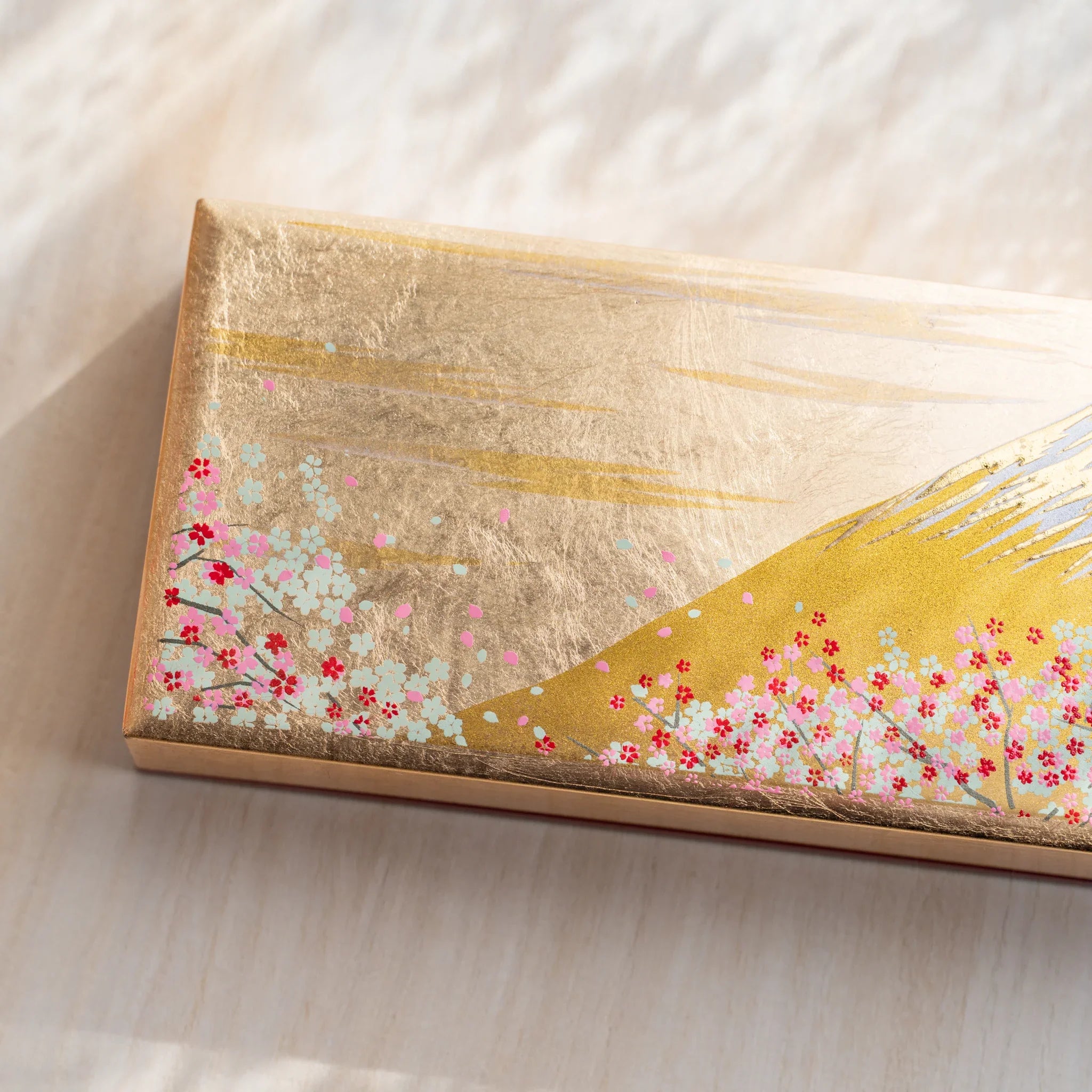 Japanese pen case shown closed from an angled side view, highlighting the gold-toned exterior and overall shape