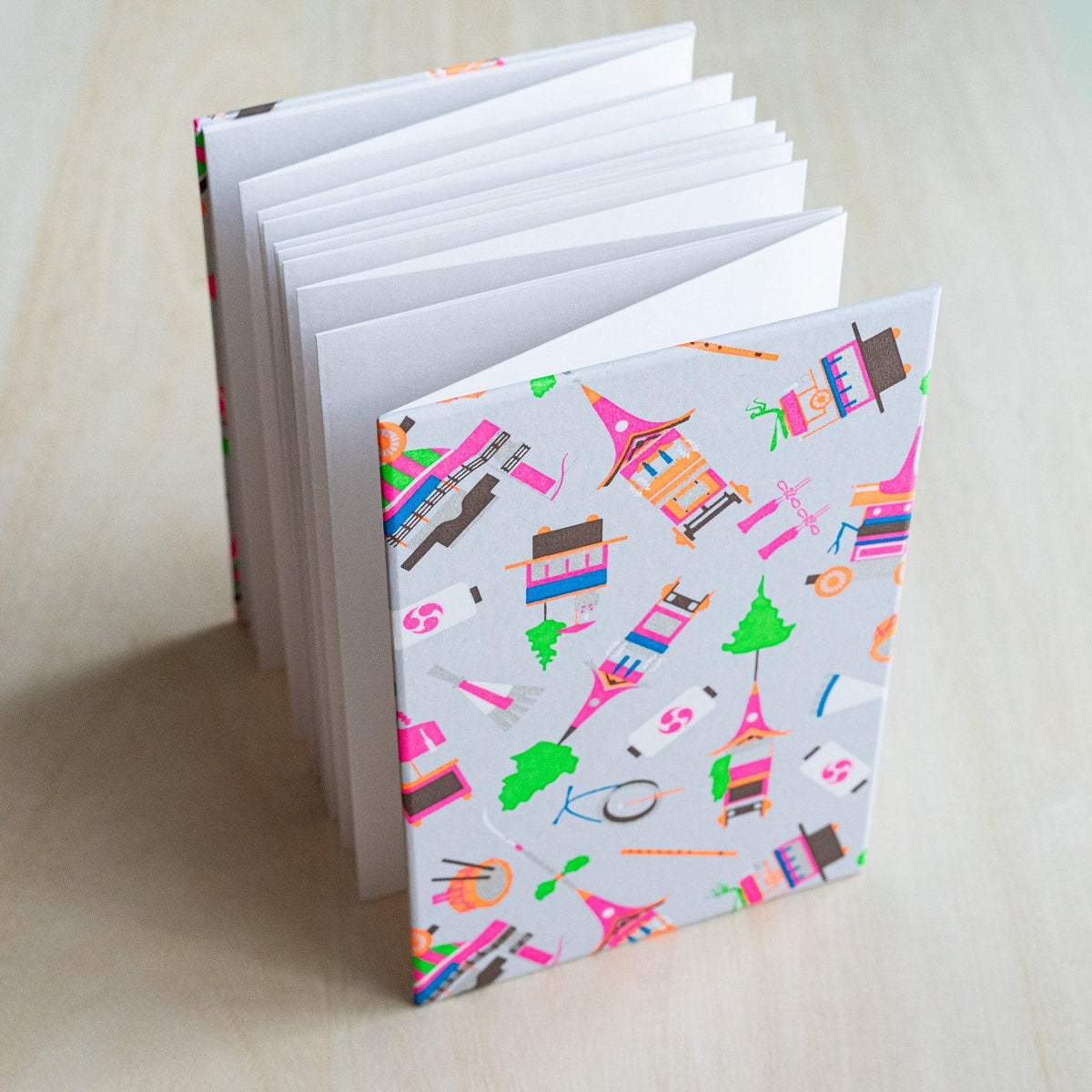 Gion Kyoto goshuincho stamp book standing open, accordion-fold white pages fanned out, pale gray cover
