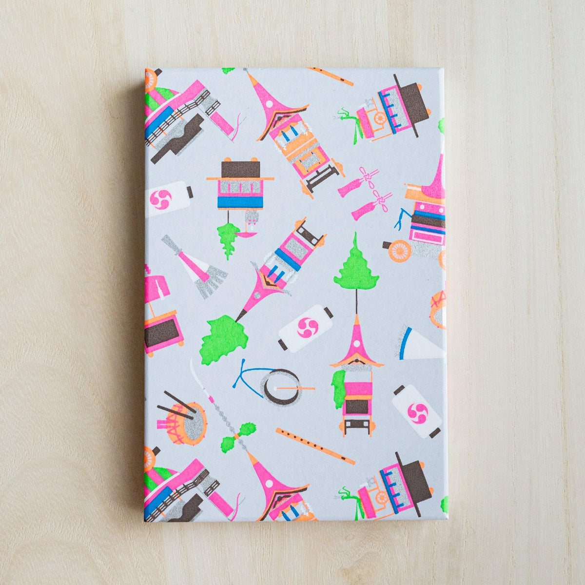 Full pale gray cover of Gion Kyoto goshuincho stamp book with neon pink, orange and green festival float motifs