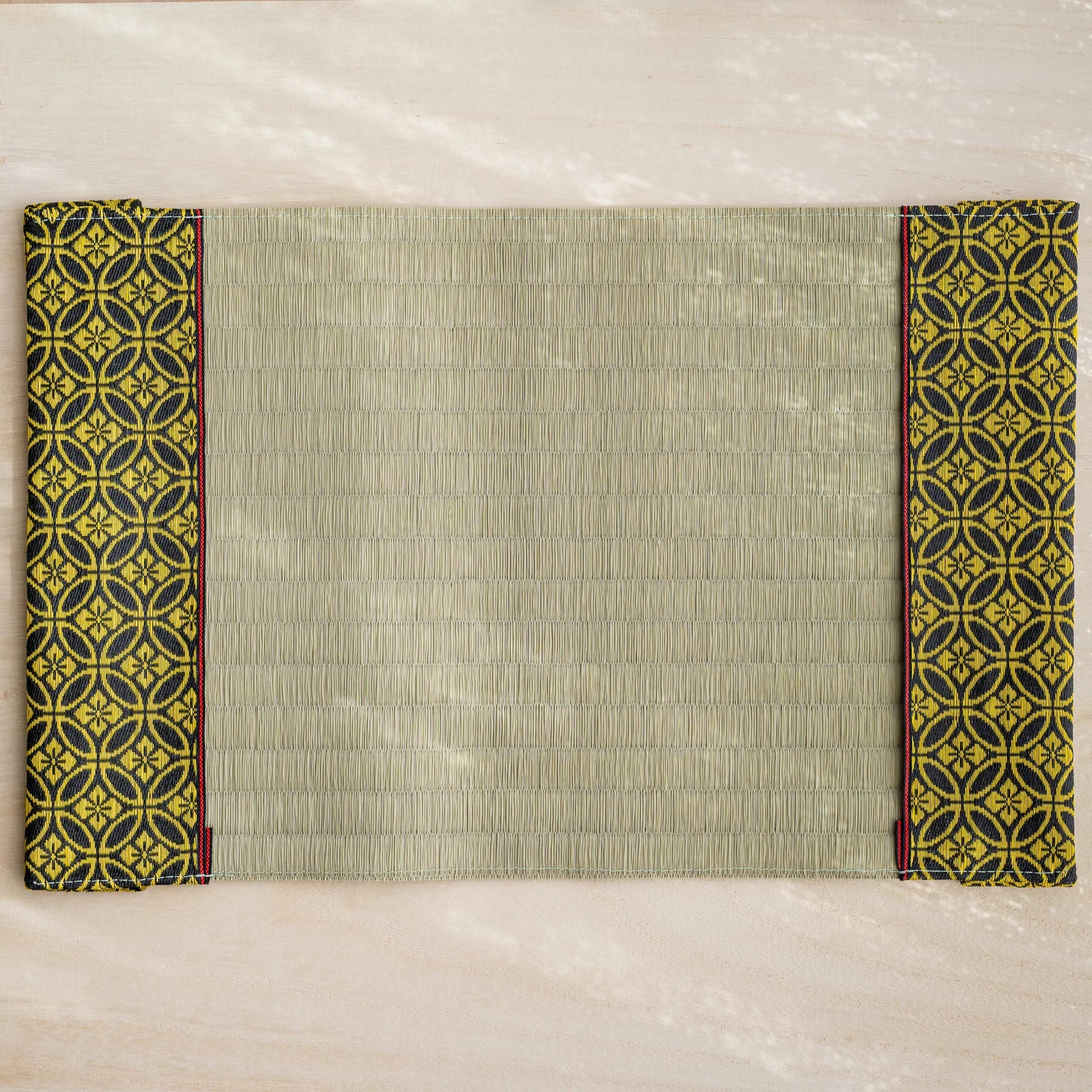 Gold Shippo tatami book cover unfolded flat, inner side up, rush straw center with patterned flaps and red striped trim