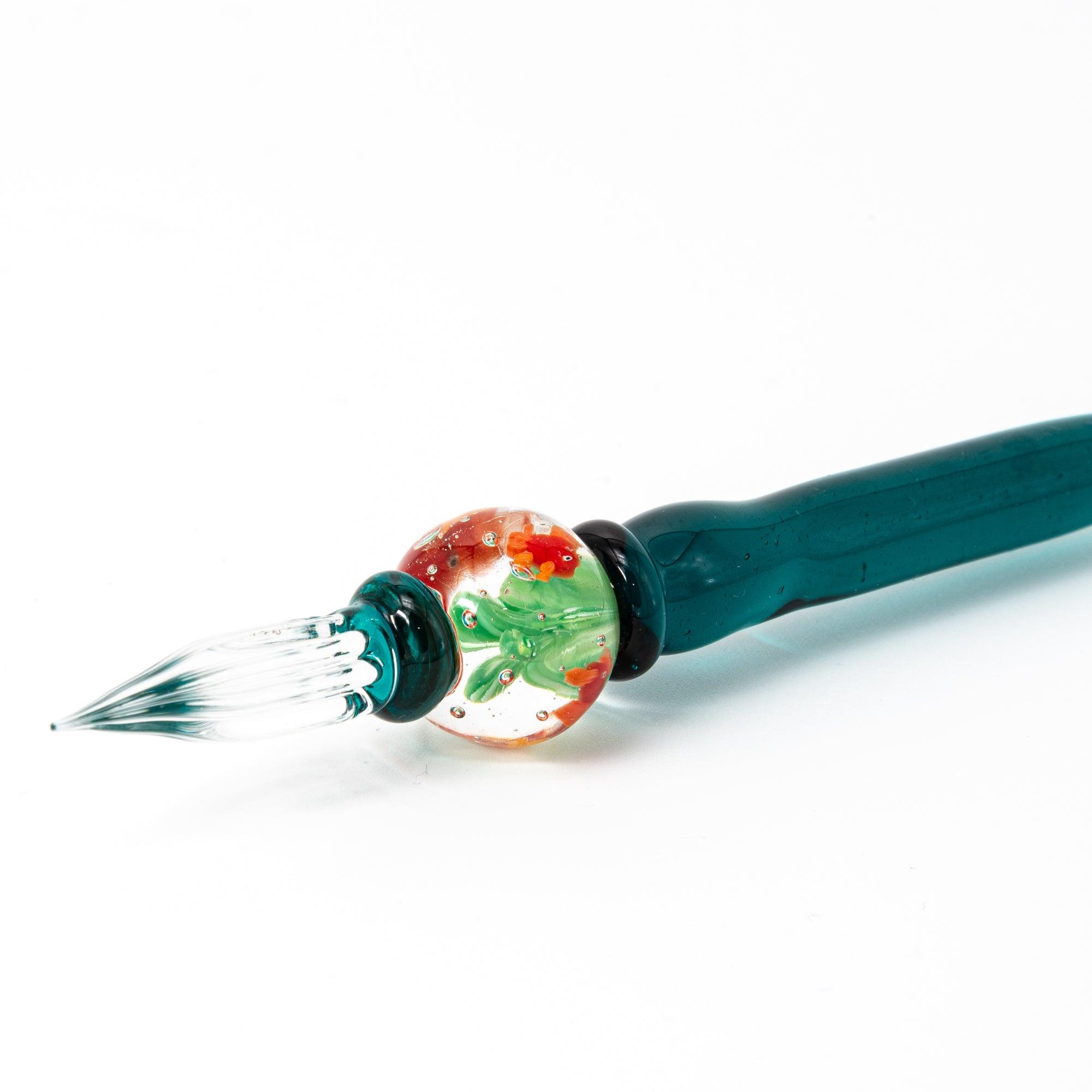 Side view of glass pen with goldfish motif encased like a fishbowl, featuring dark green handle.