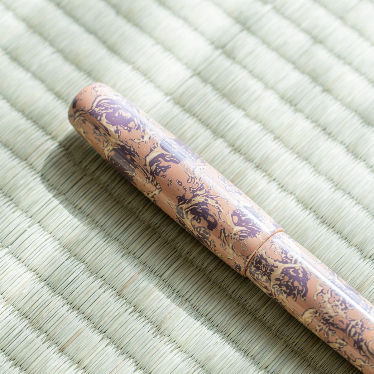 Close-up of the Hanagasumi cap, pink urushi with a purple floral-like pattern and the cap joint