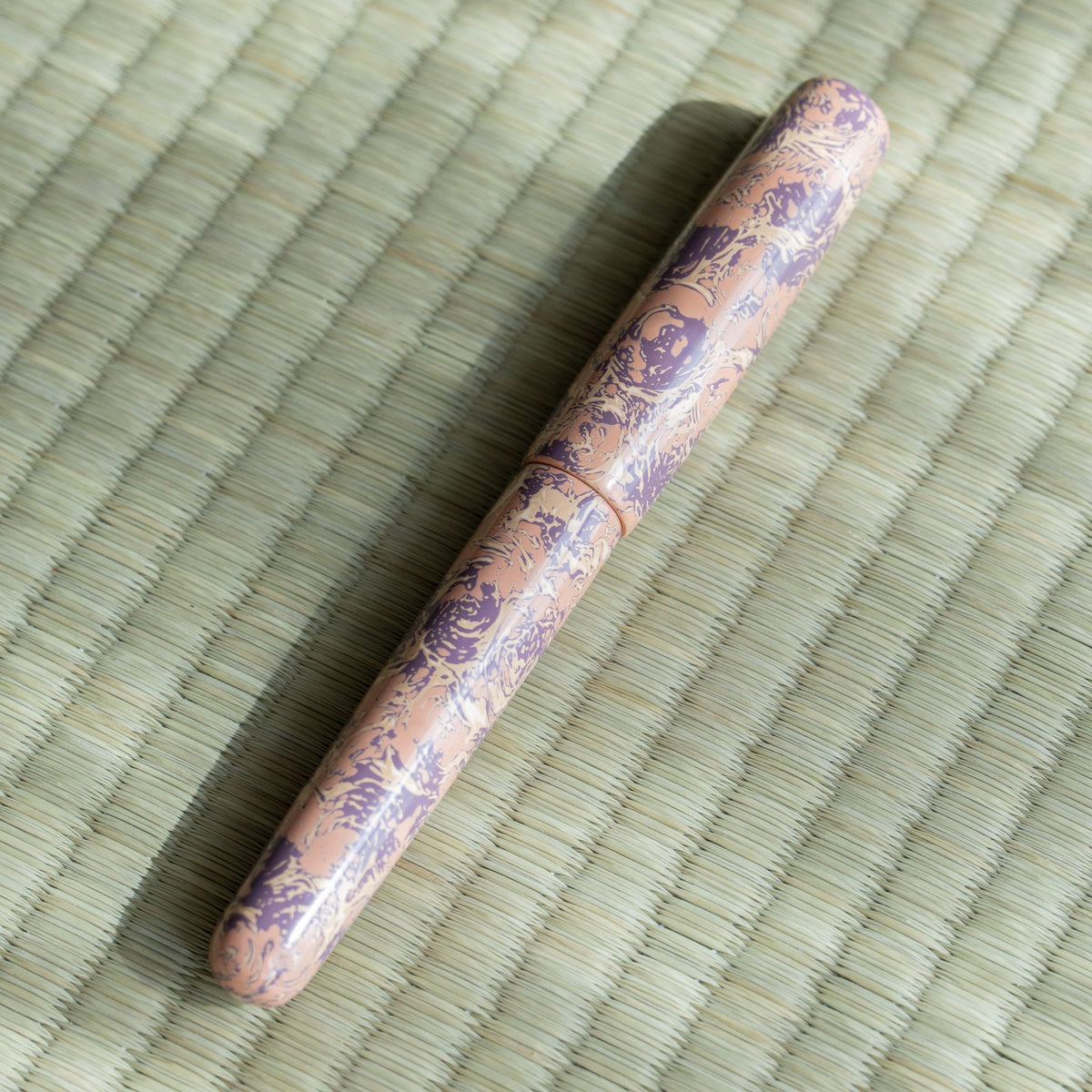 Capped Hanagasumi Tsugaru-nuri fountain pen on tatami in soft light, pink lacquer with purple pattern