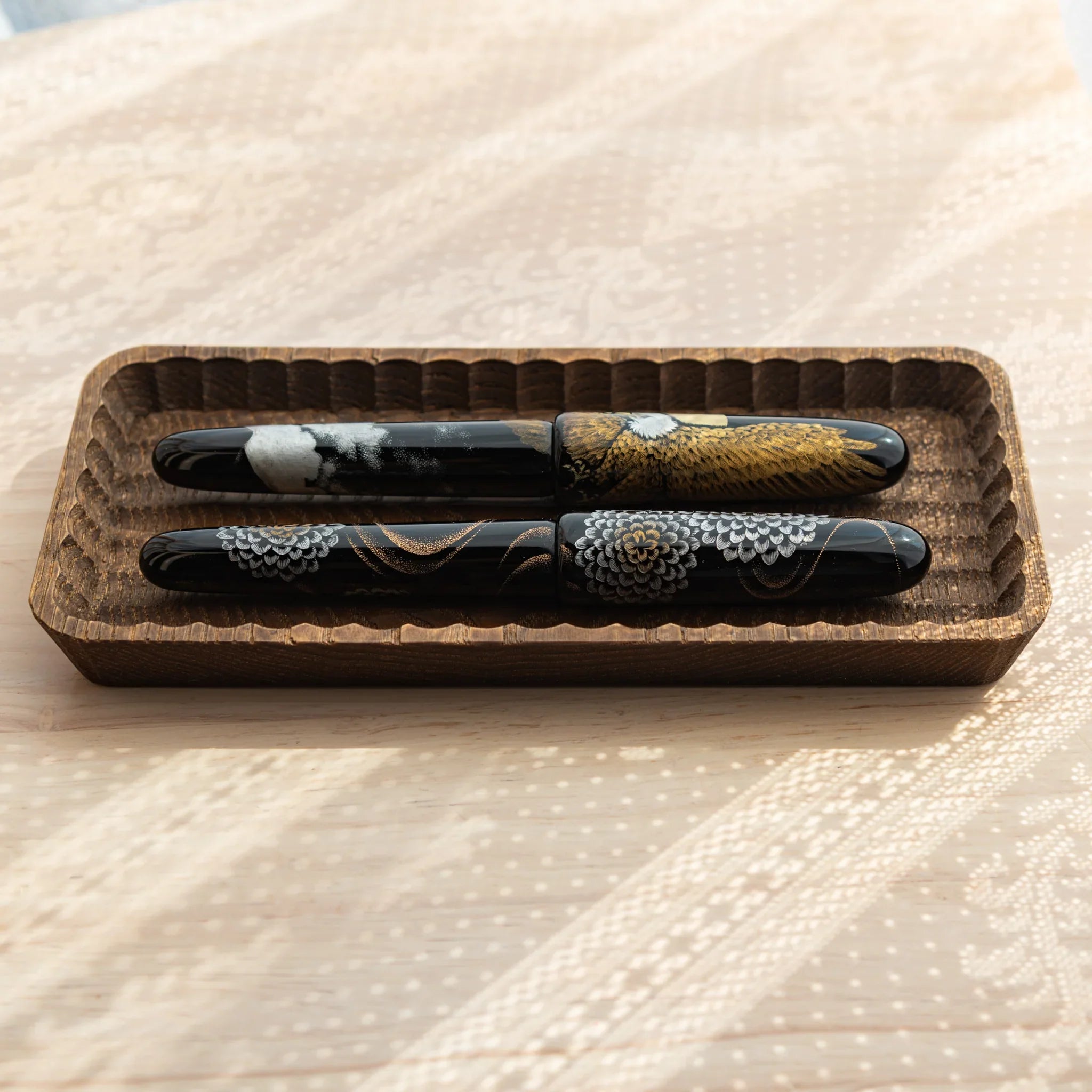 Lacquered Japanese Fountain Pens with intricate designs displayed in a handcrafted Japanese Pen Tray.