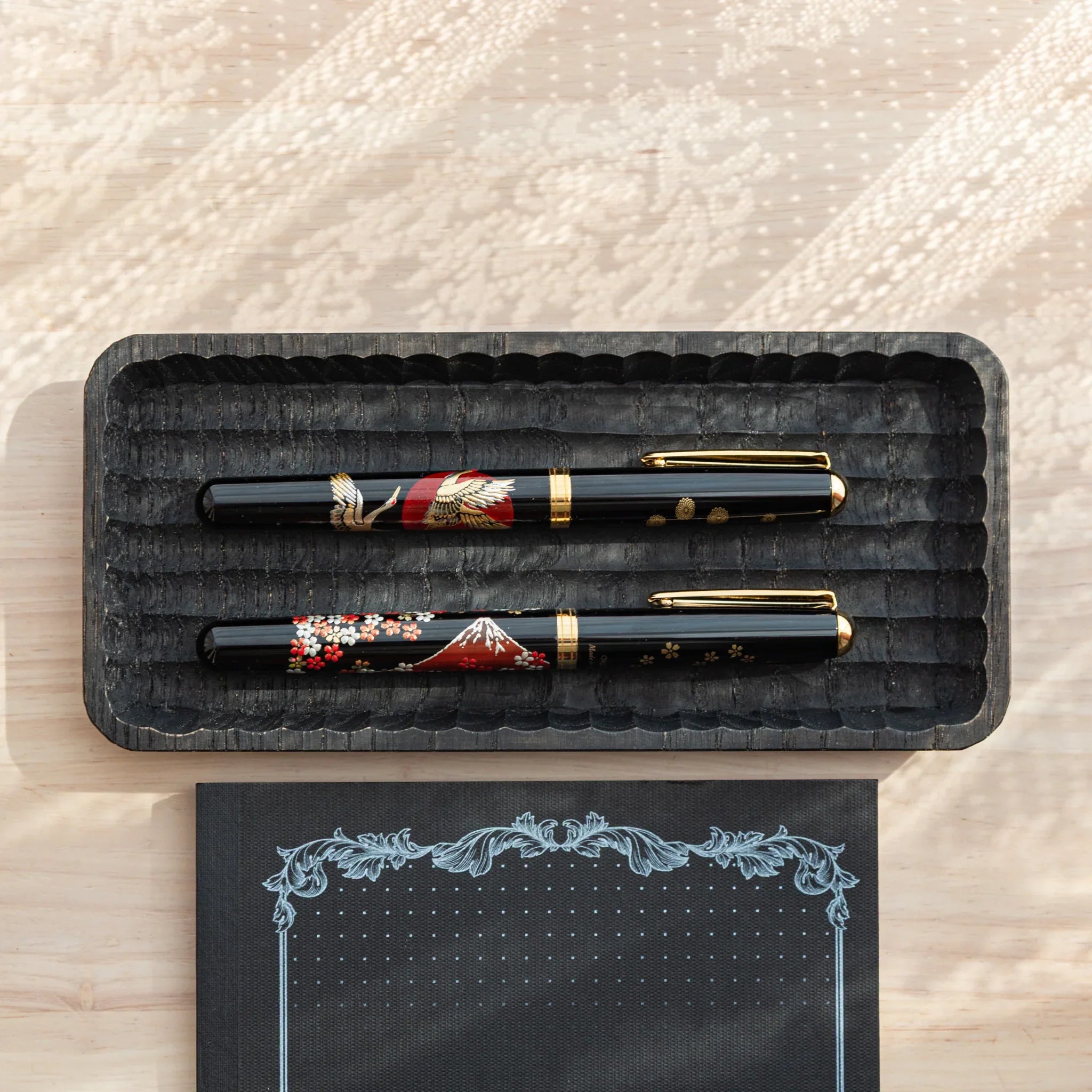 Japanese Fountain Pens with crane and chrysanthemum motifs displayed in a Wagatabon Black Pen Tray.