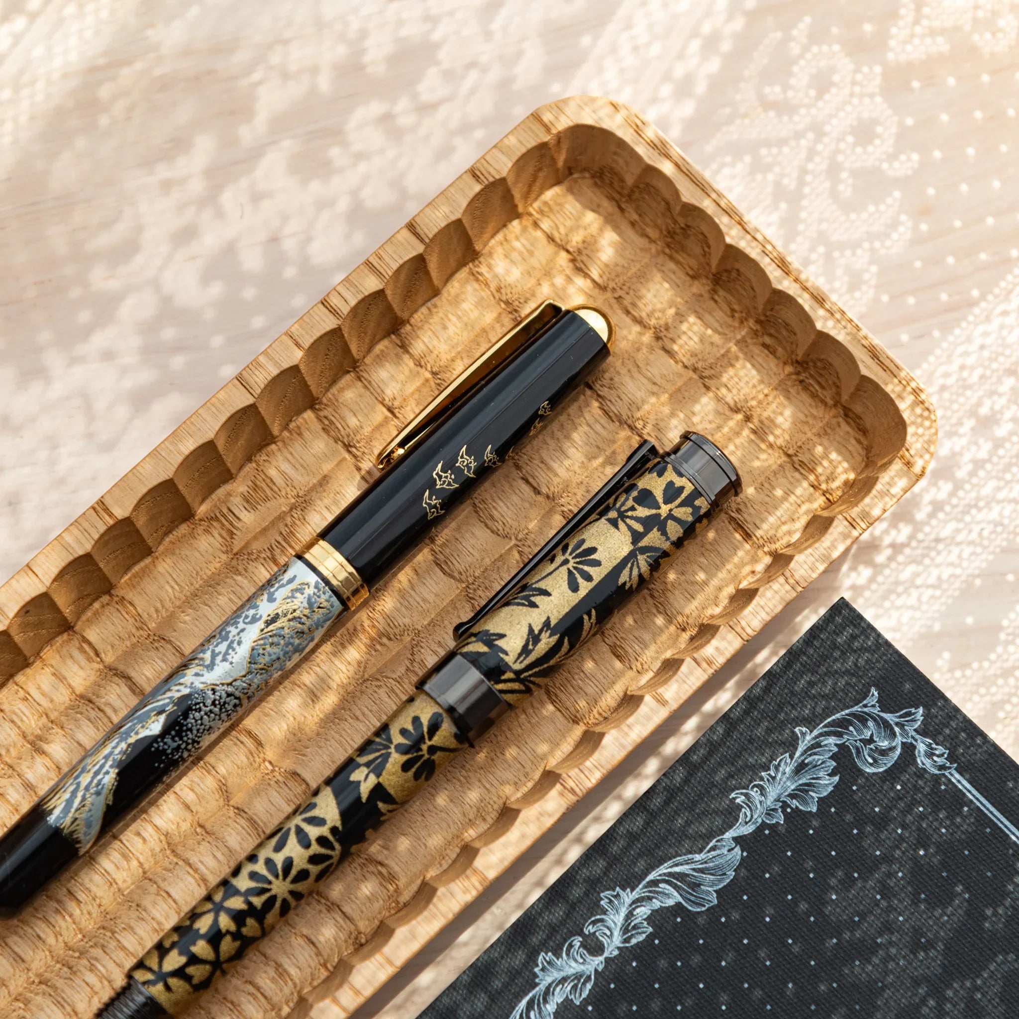 Close-up of Hand-Carved Slim Wagatabon Pen Tray with Japanese Fountain Pens featuring gold floral motifs.