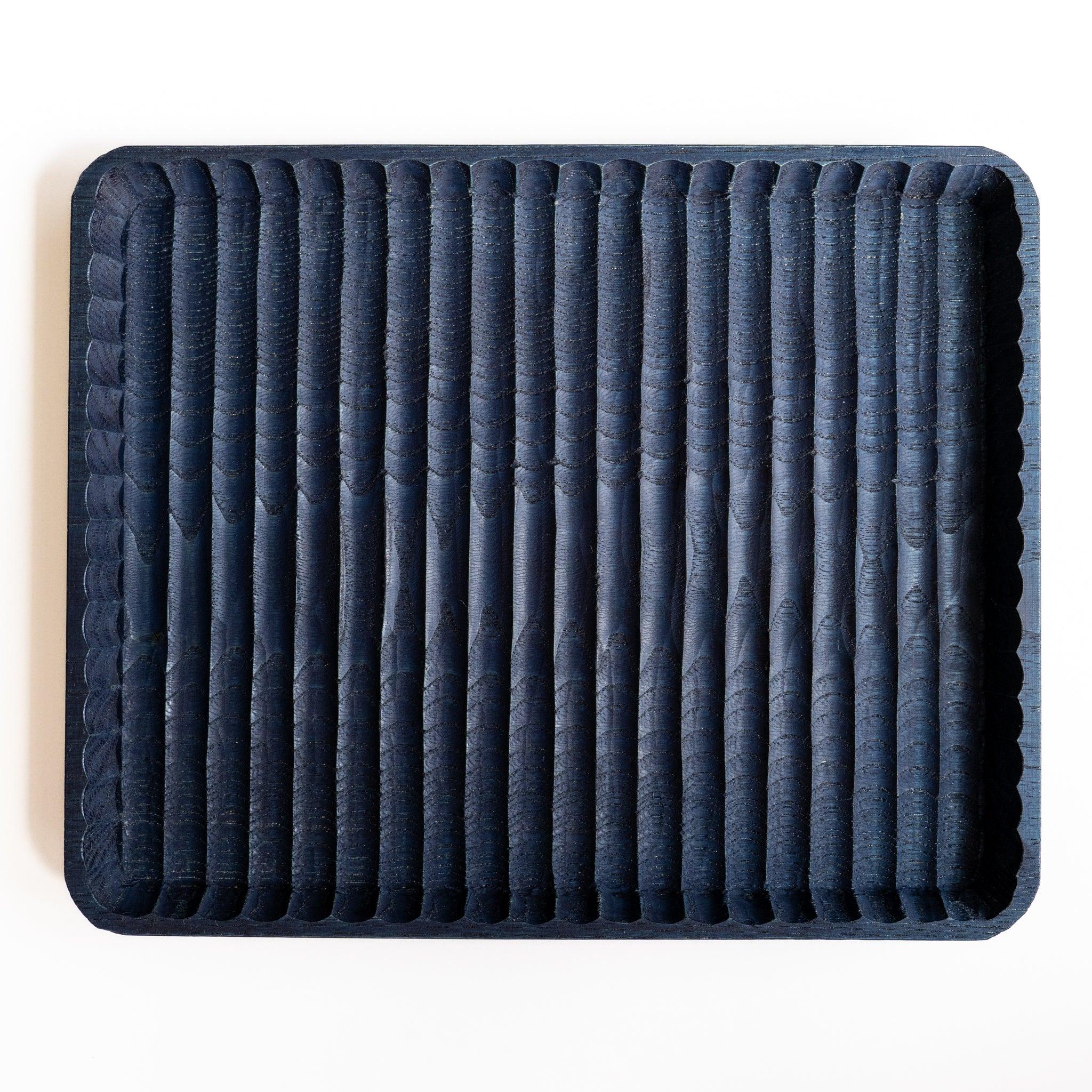 Empty indigo dyed wide Wagatabon chestnut pen tray from above with parallel hand-carved grooves and scalloped rim