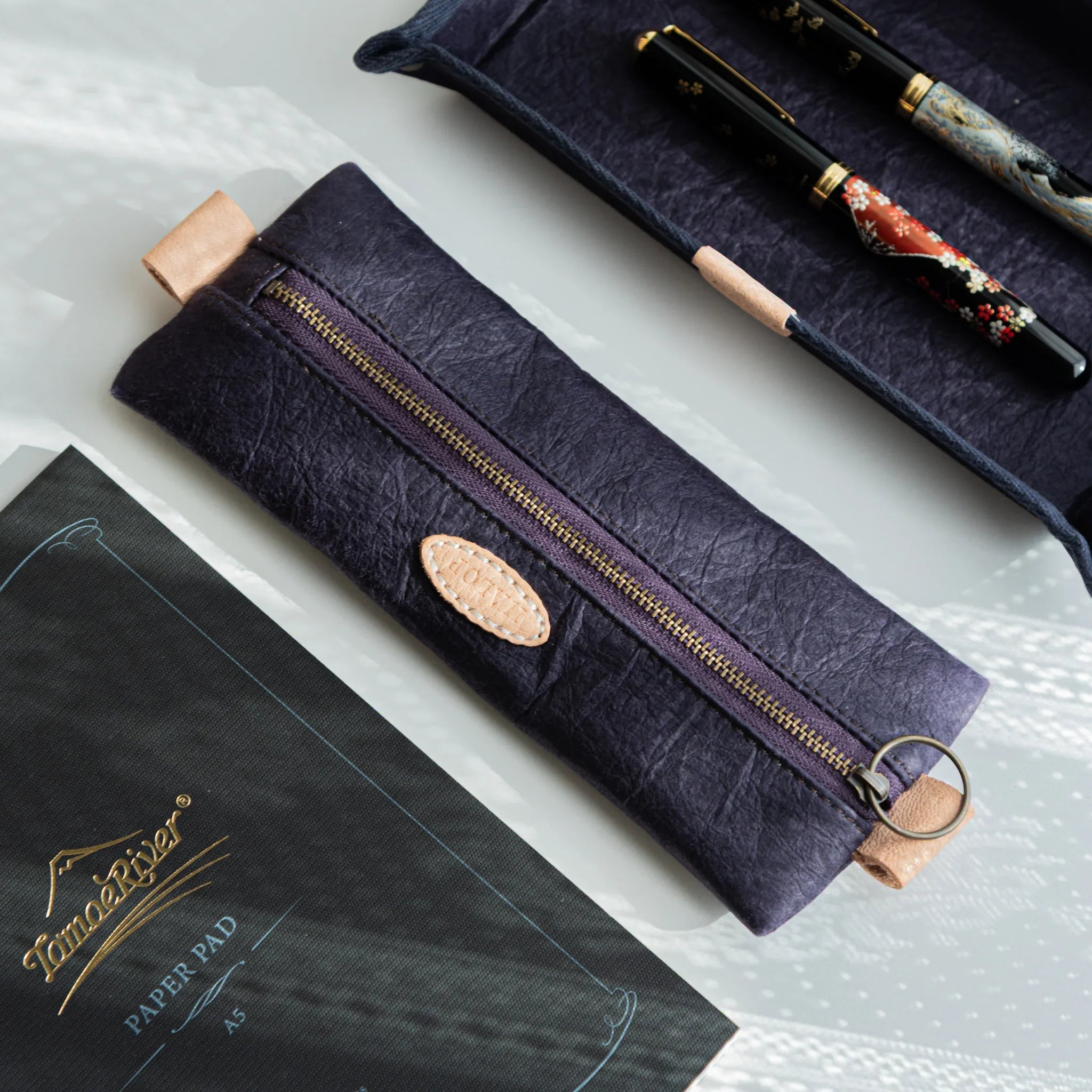 Handcrafted Sugihara Washi Japanese Pen Case in purple beside two Japanese Fountain Pens and Tomoe River notebook.