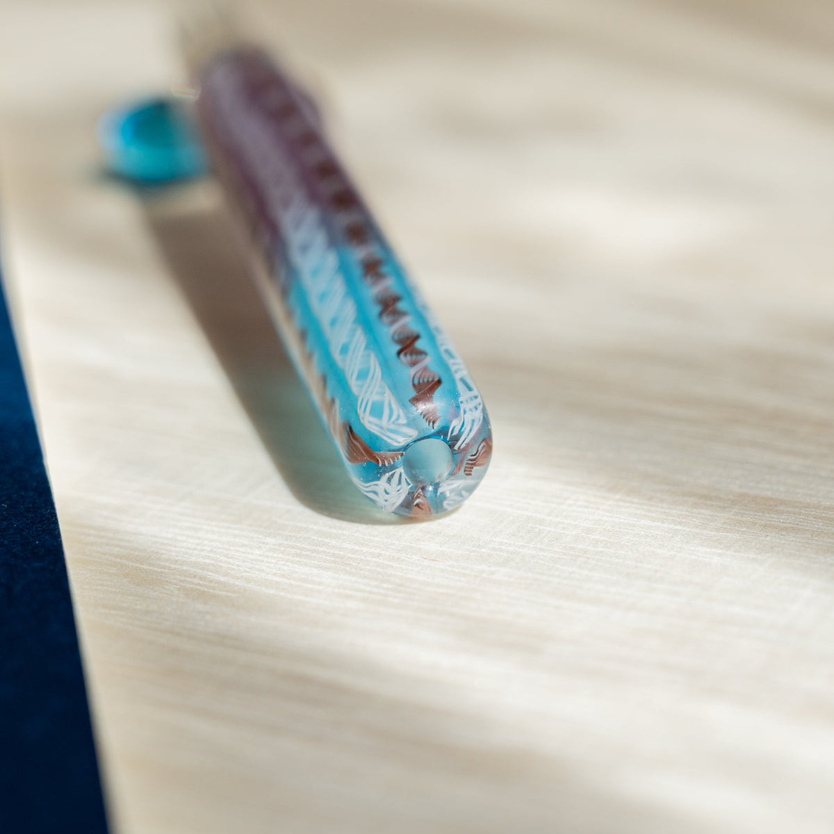 Close-up of the Helix Dawn barrel end showing turquoise and pink glass canes in a white lattice twist