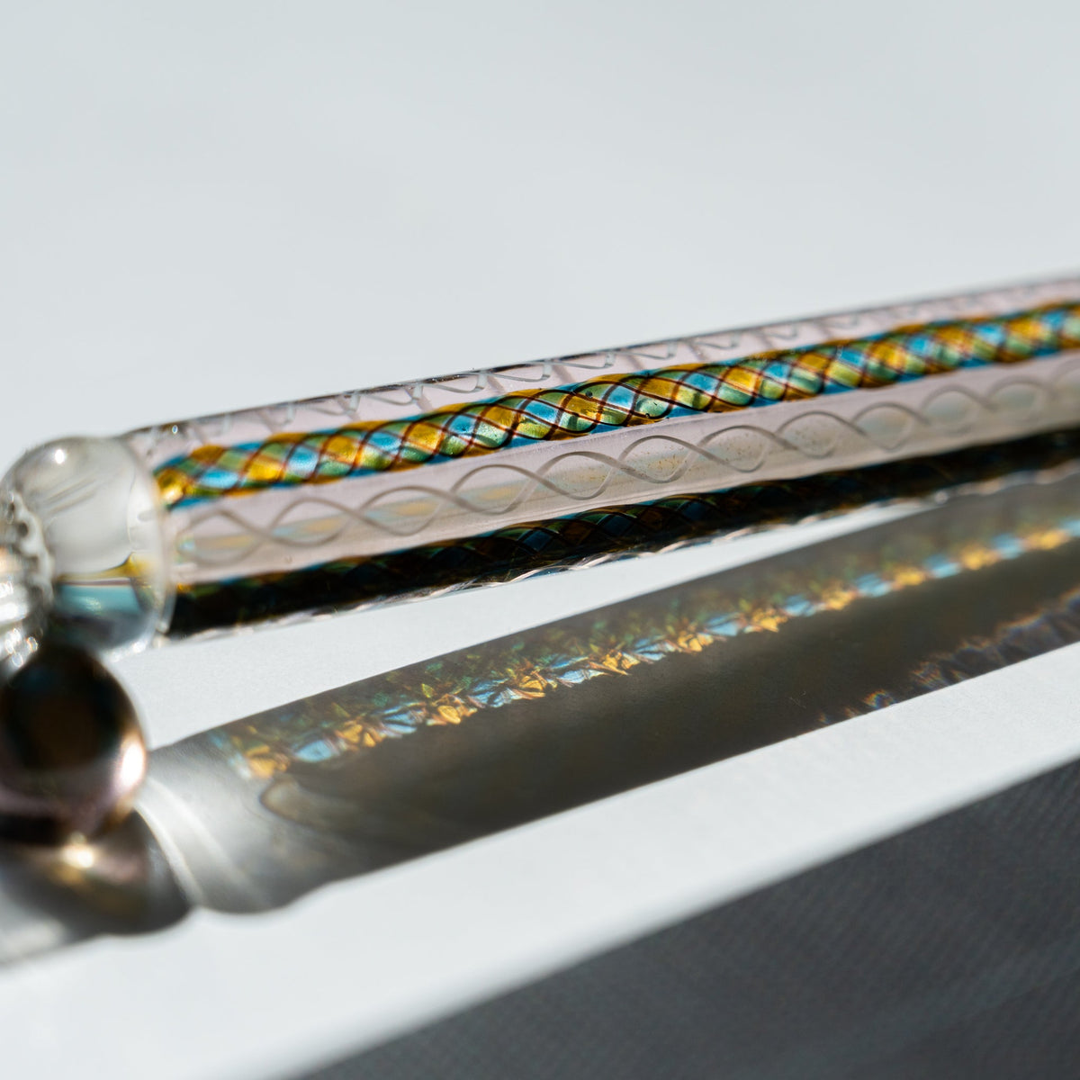 Close-up of the Helix Peacock barrel showing teal and gold diamond canes beside white spiral twists