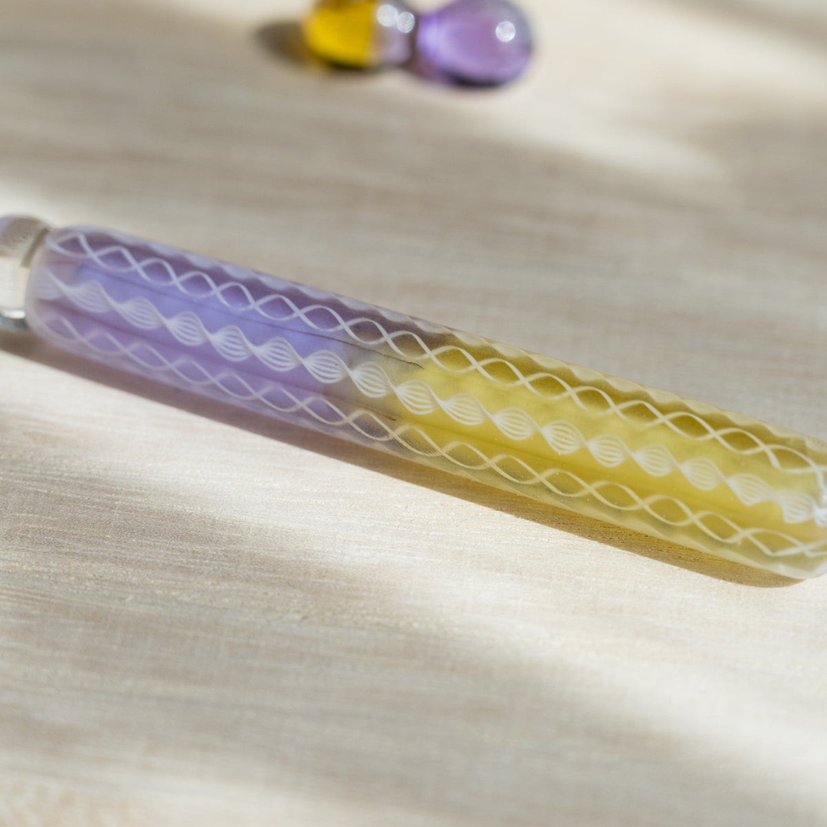 Close-up of the Helix Wisteria barrel where lavender meets yellow glass under white spiral lace canes