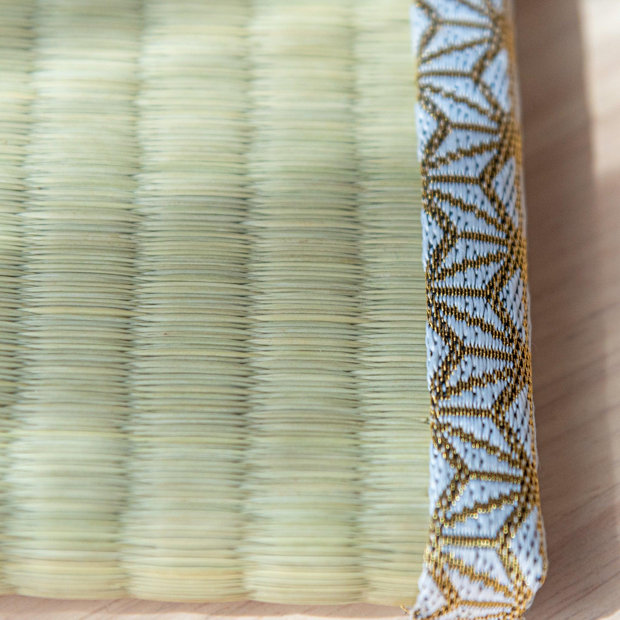 A close-up of the tatami-style pen tray’s woven texture and gold-patterned trim.  