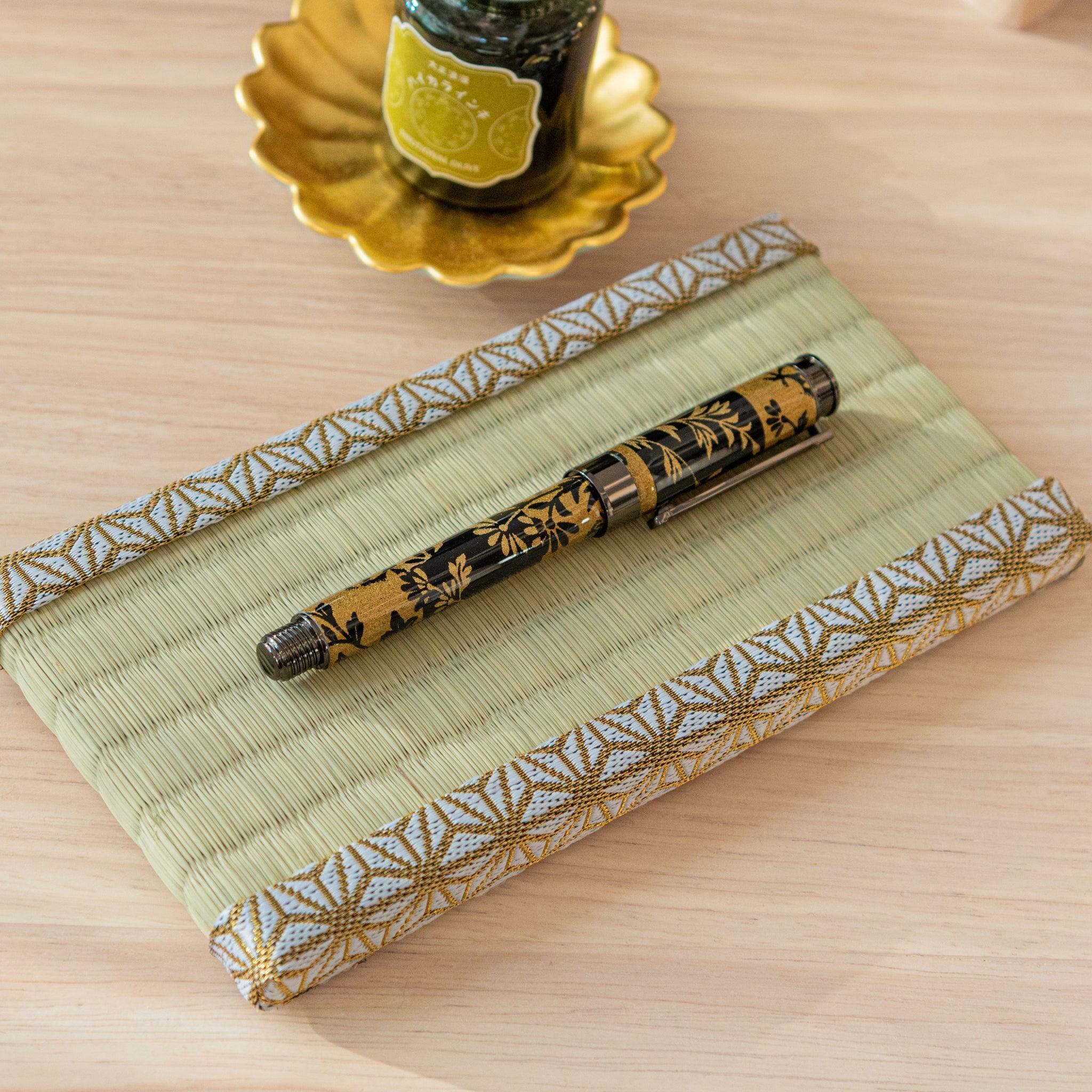 A close-up of the tatami-style pen tray’s woven texture and gold-patterned trim.  