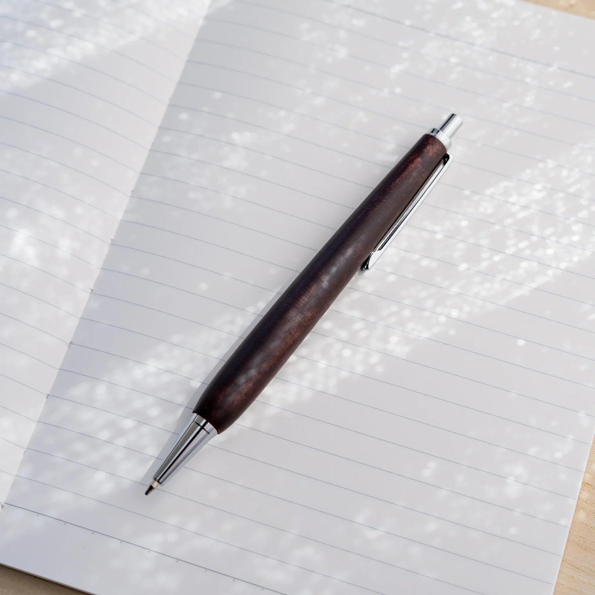 Horse chestnut wood urushi lacquered ballpoint pen in chocolate brown on white paper, Japanese wood