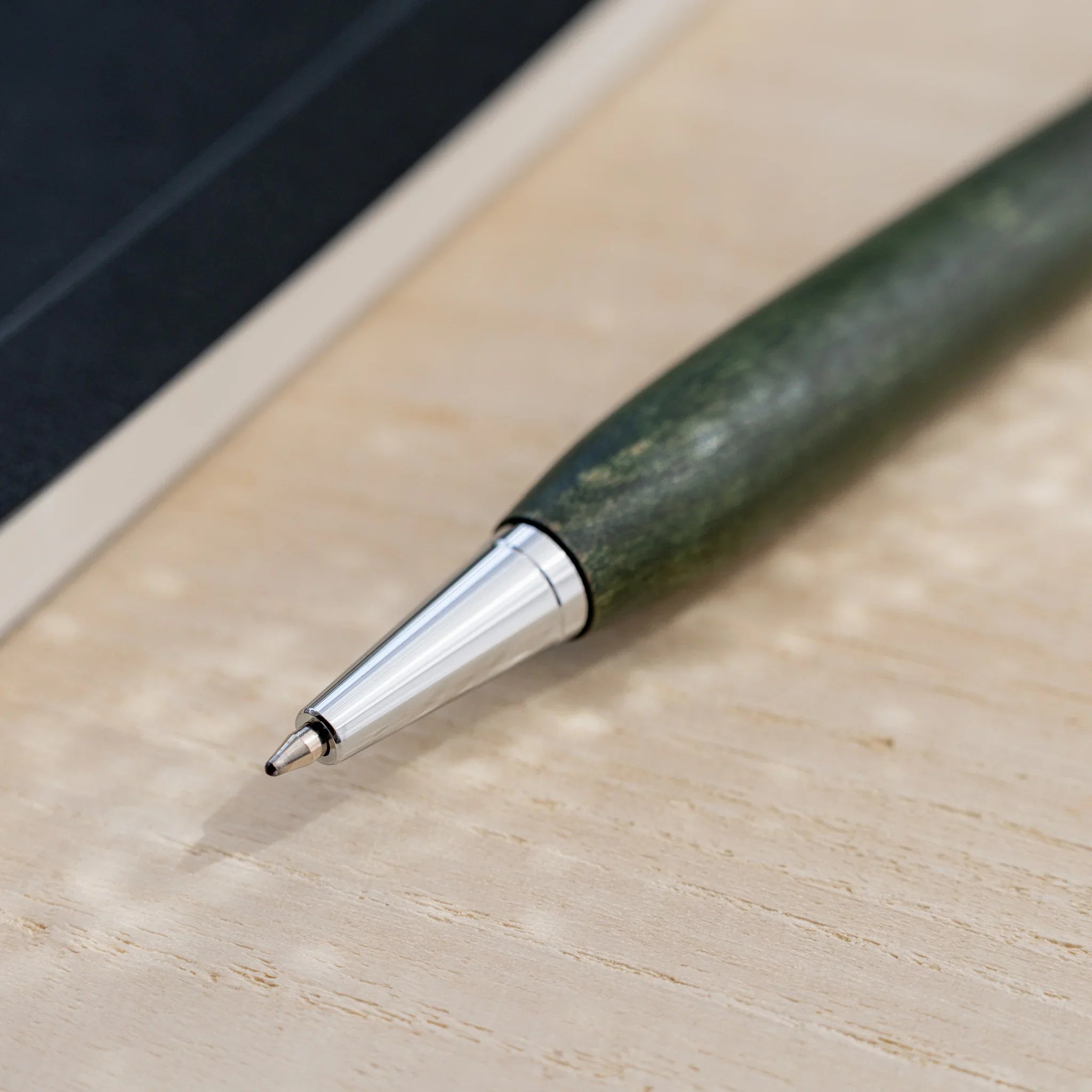 Olive green horse chestnut wood urushi ballpoint pen, close-up of silver cone tip and writing point, Japanese wood
