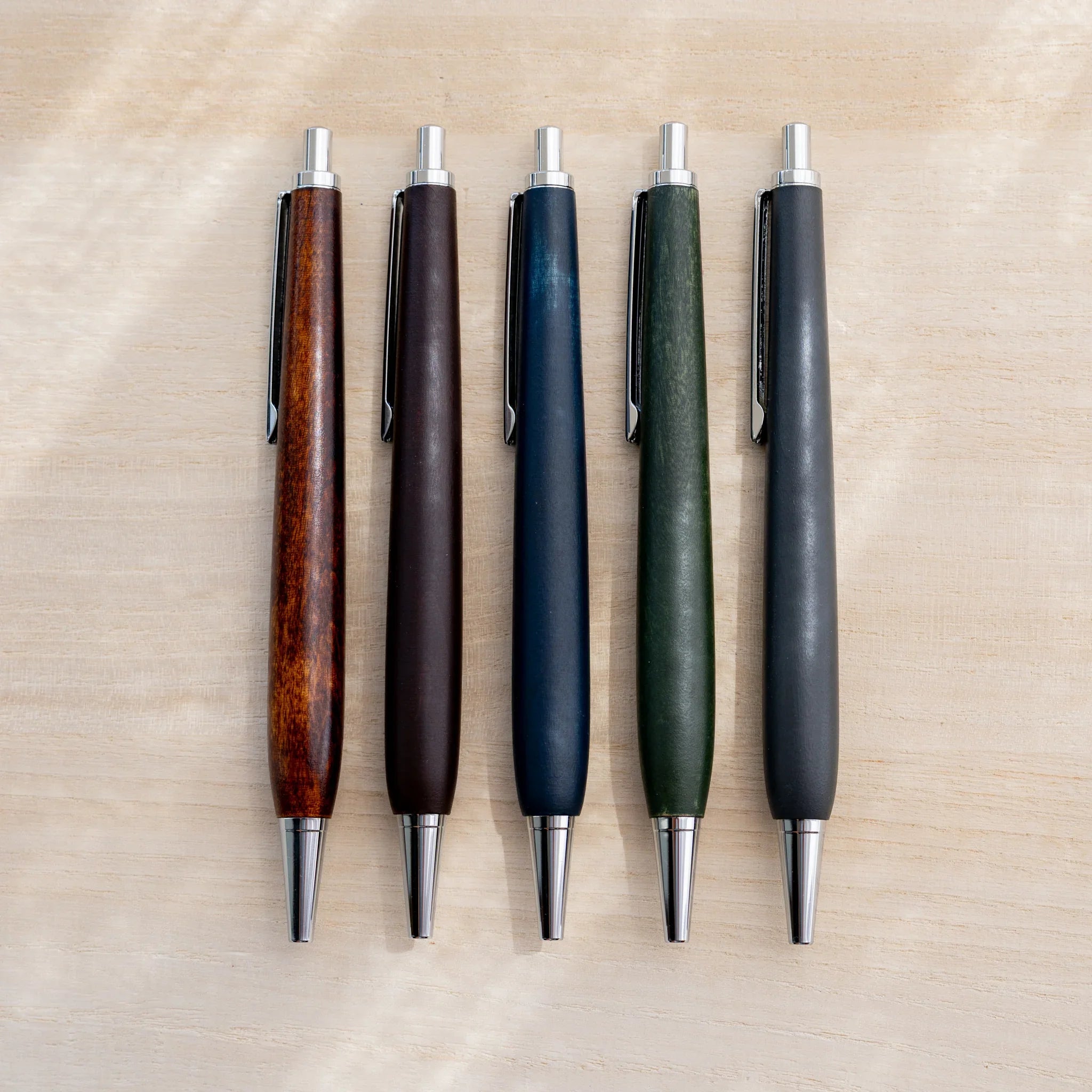 Five horse chestnut wood urushi lacquered ballpoint pens in amber, brown, indigo, green and black, Japanese wood