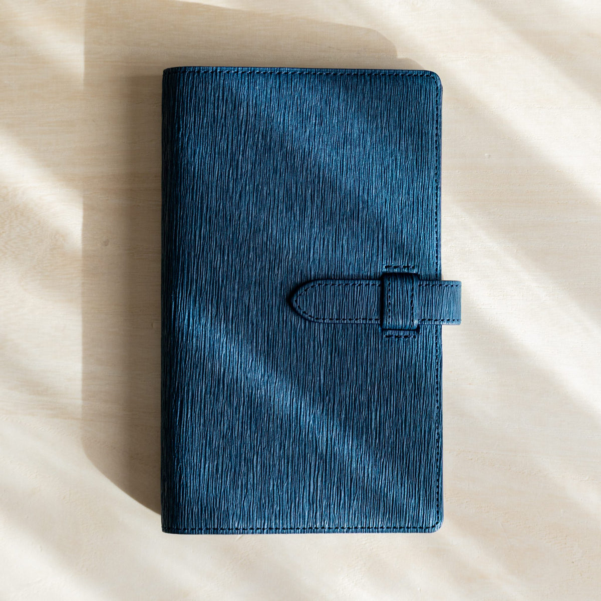 Ise Gikakushi paper leather planner, Bible size in navy, closed with creased cover and belt strap