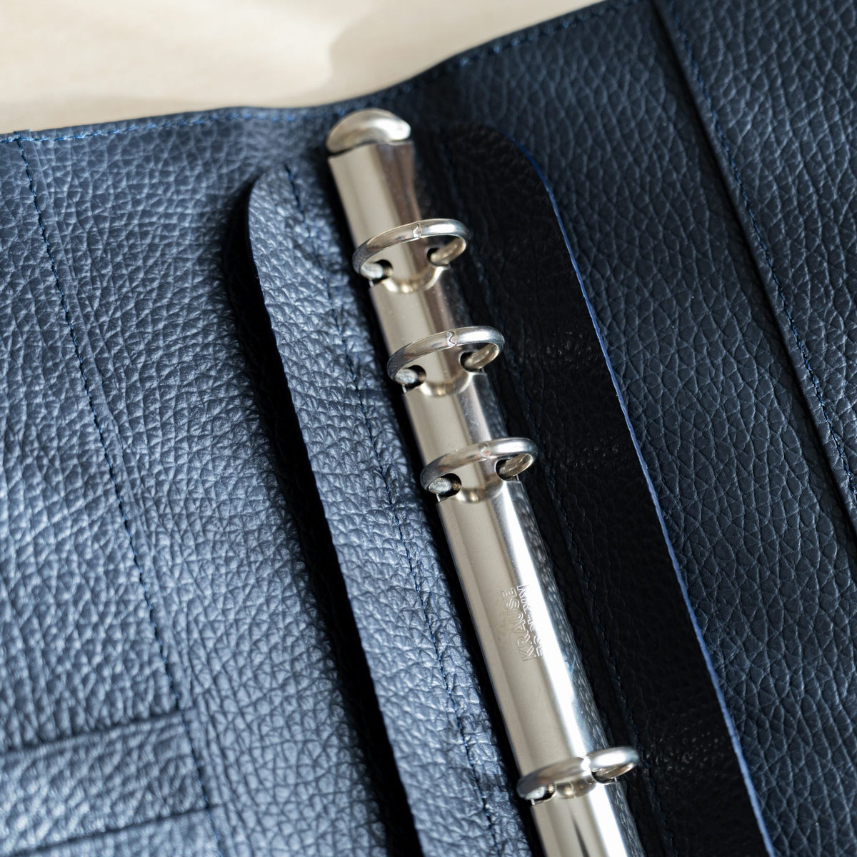 Close-up of silver binder rings on the navy grained leather interior of the Ise Gikakushi planner