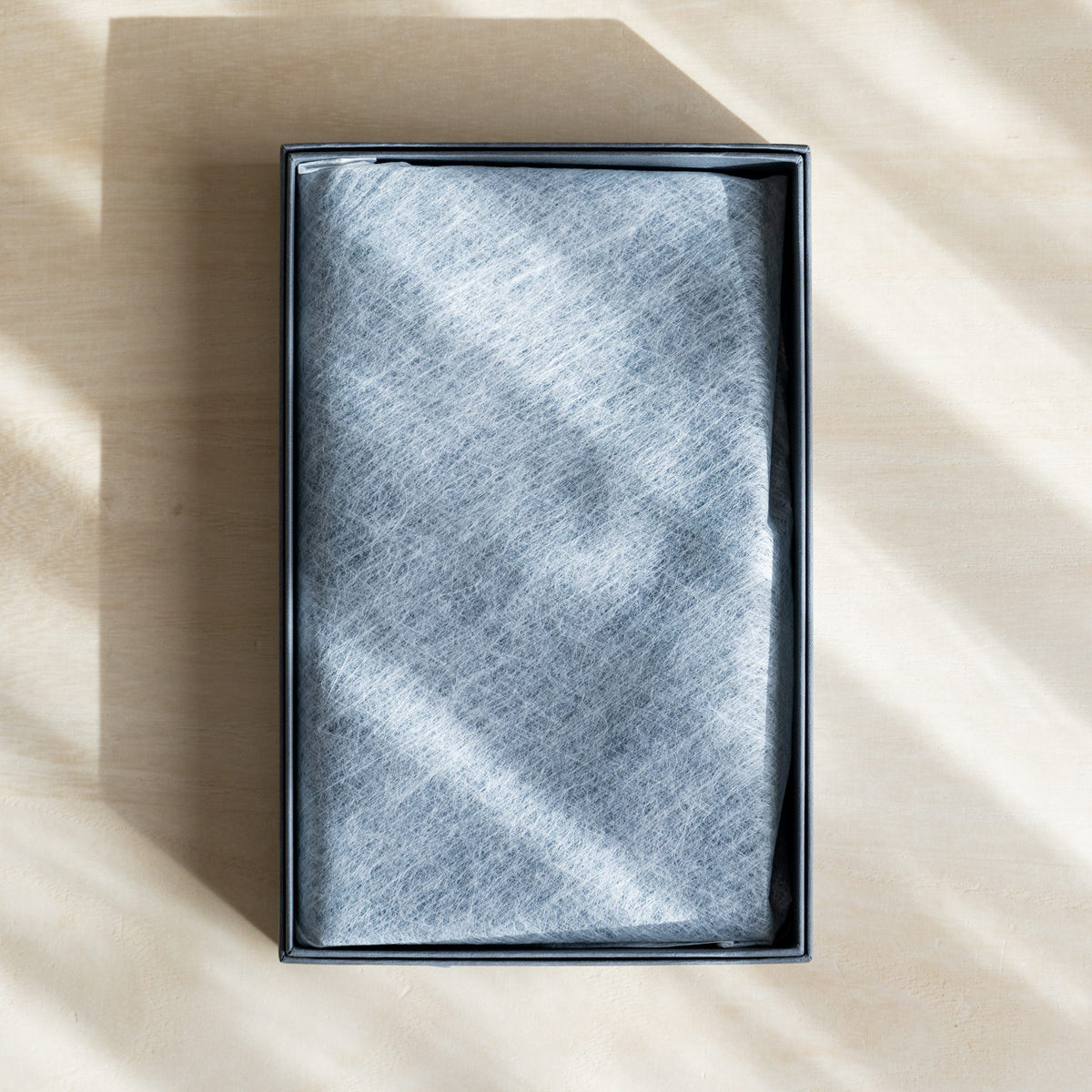 Open gift box with the planner wrapped in white nonwoven cloth