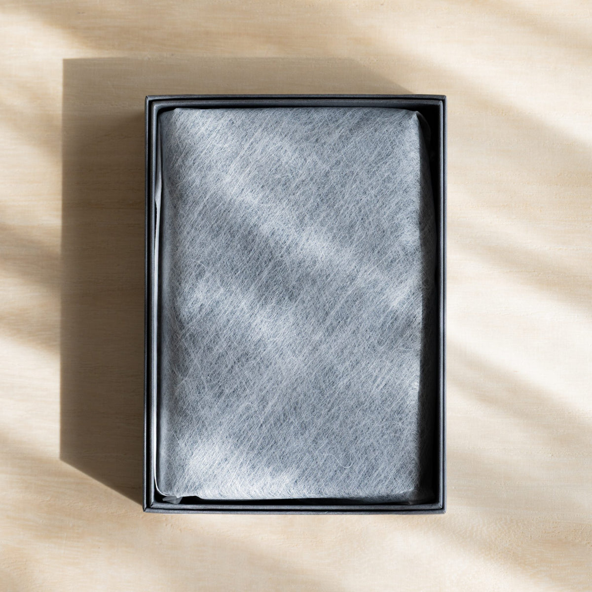 Planner wrapped in white nonwoven cloth inside an open dark gray box