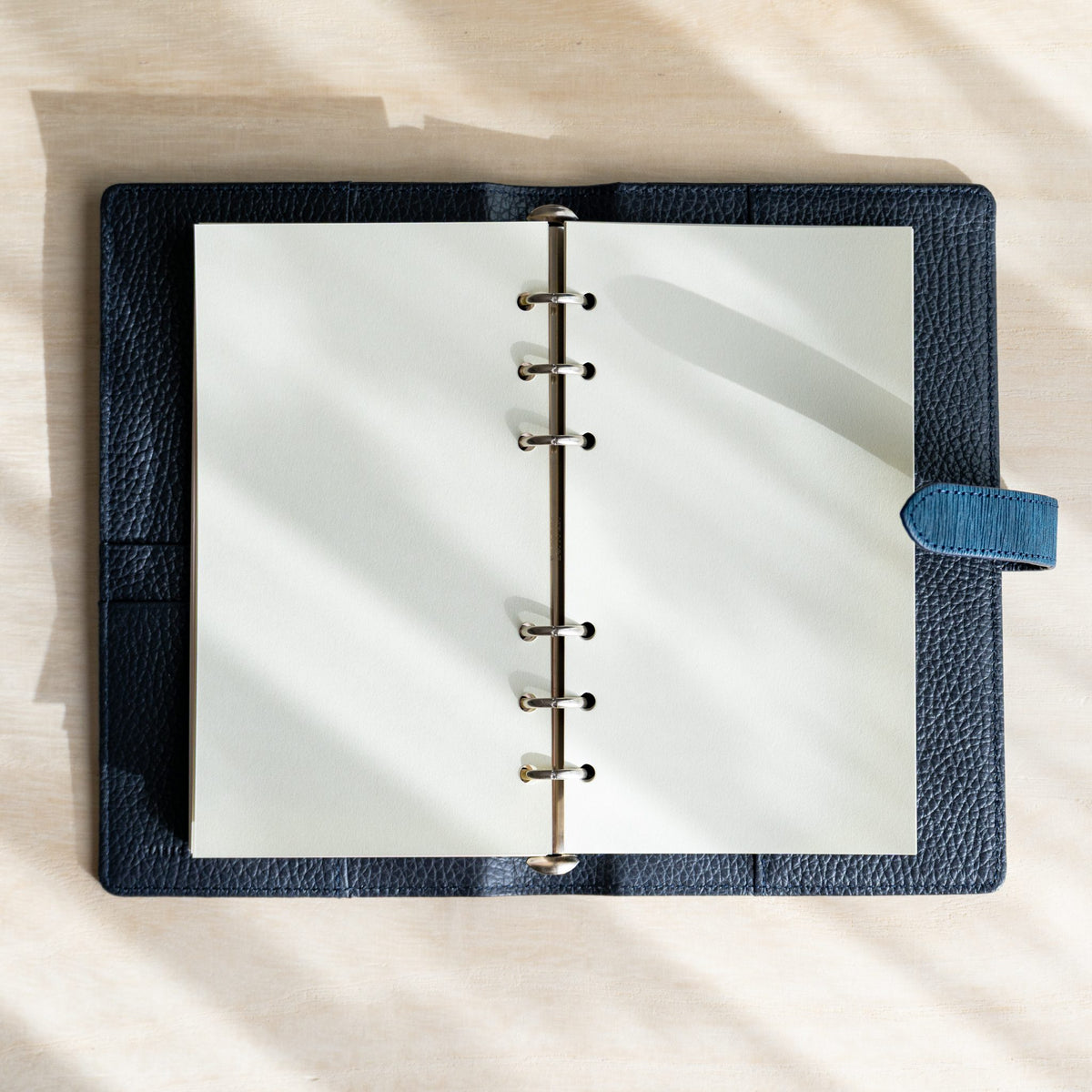 Open navy Ise Gikakushi planner with cream pages on silver rings and a blue strap tab
