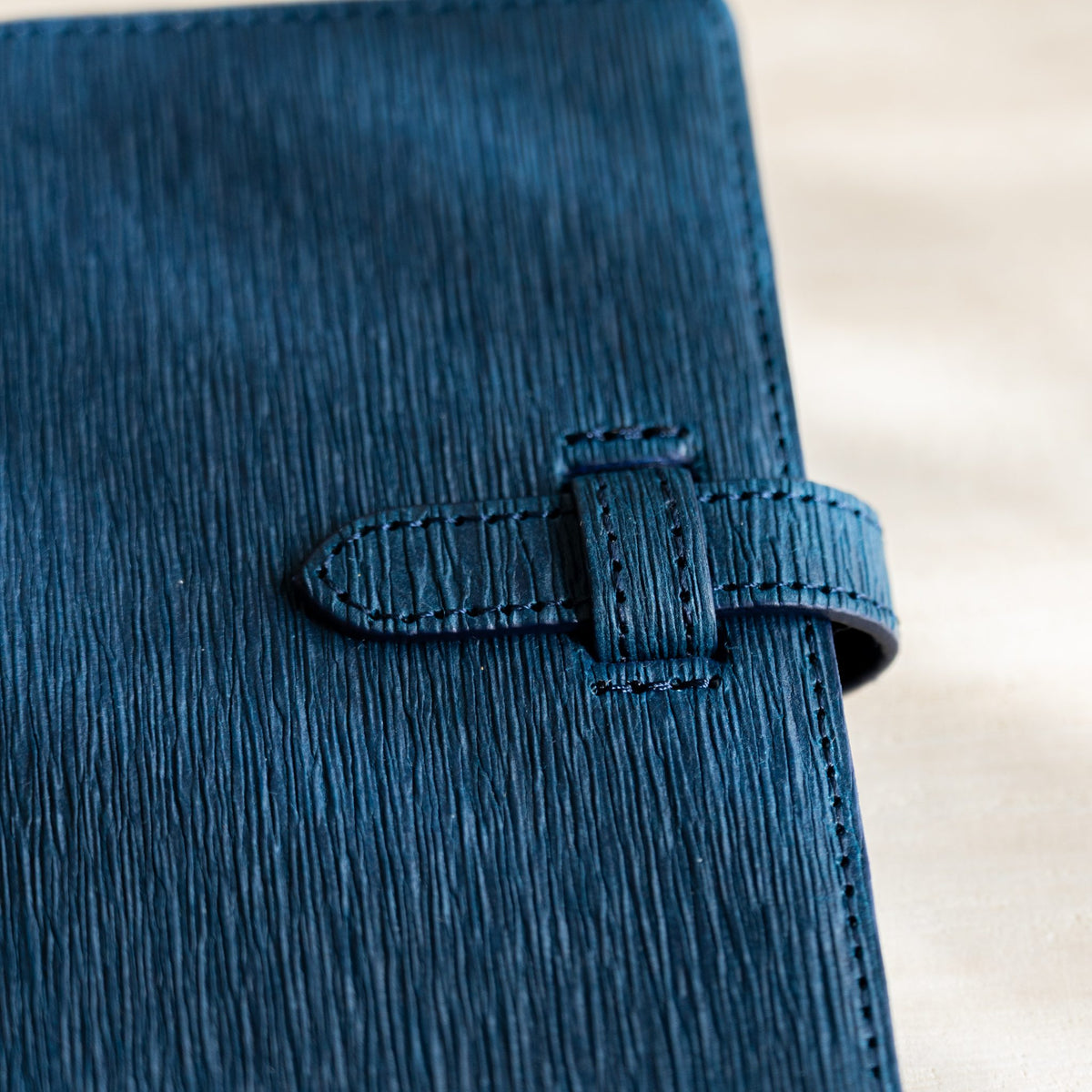 Close-up of the navy crease texture and stitched strap on the planner cover