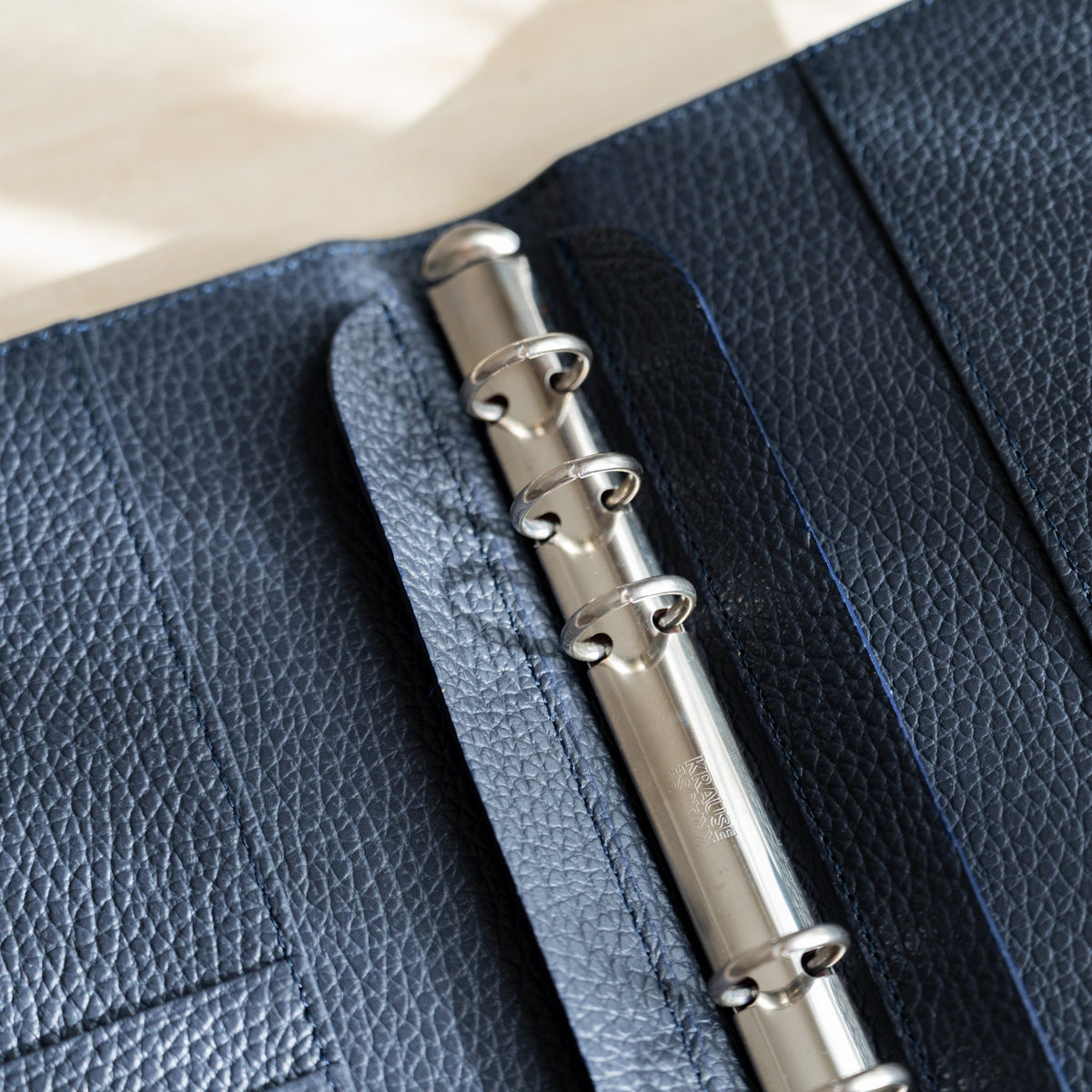 Close-up of opened silver binder rings on the navy pebbled leather interior