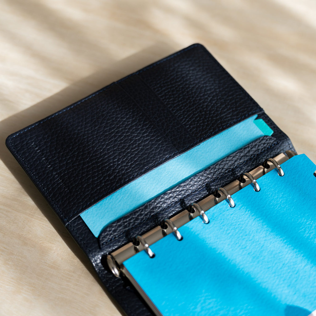Sky blue hole-punched strip in the inner pocket beside sky blue pages on the silver rings