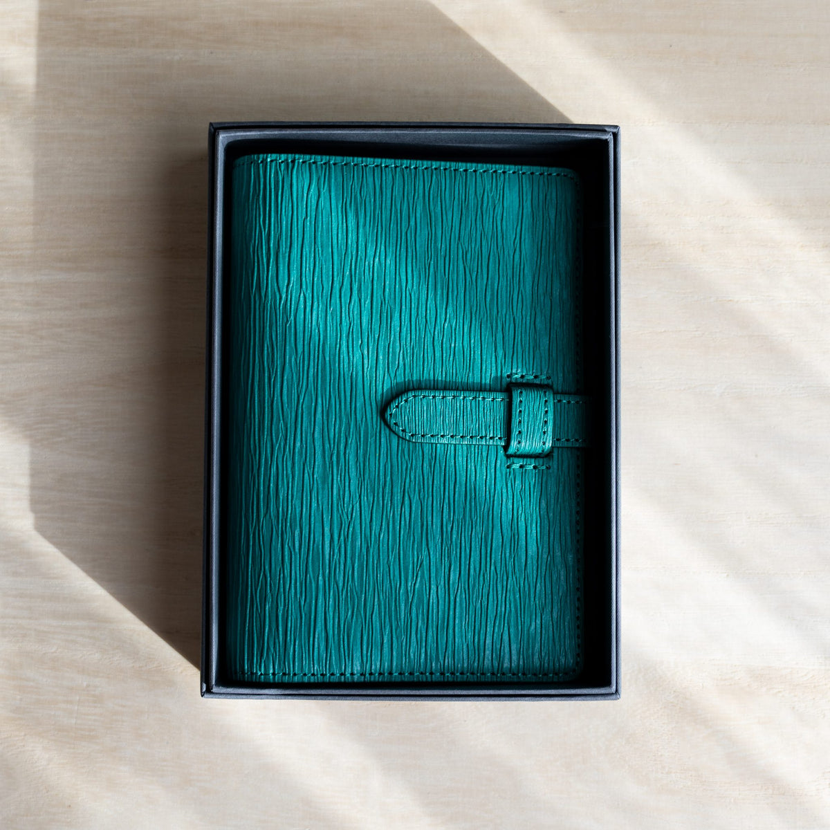 Teal Ise Gikakushi paper leather planner placed in its open gray gift box