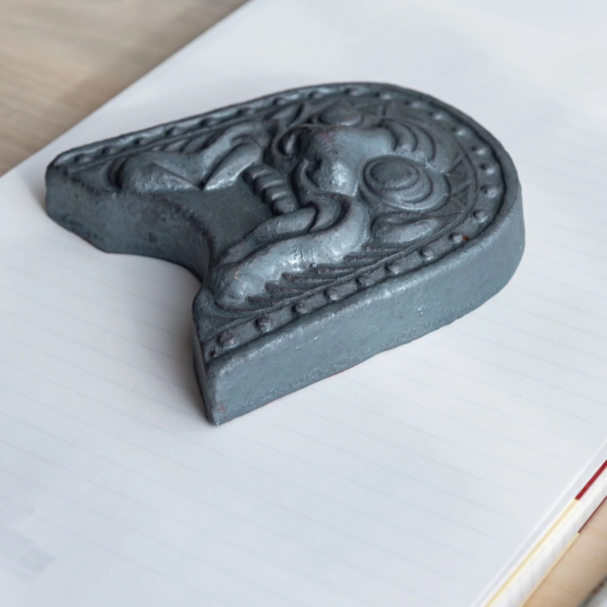 Onigawara-motif Japanese paperweight. A low-angle shot of the desk accessory resting prominently on a sheet of paper.