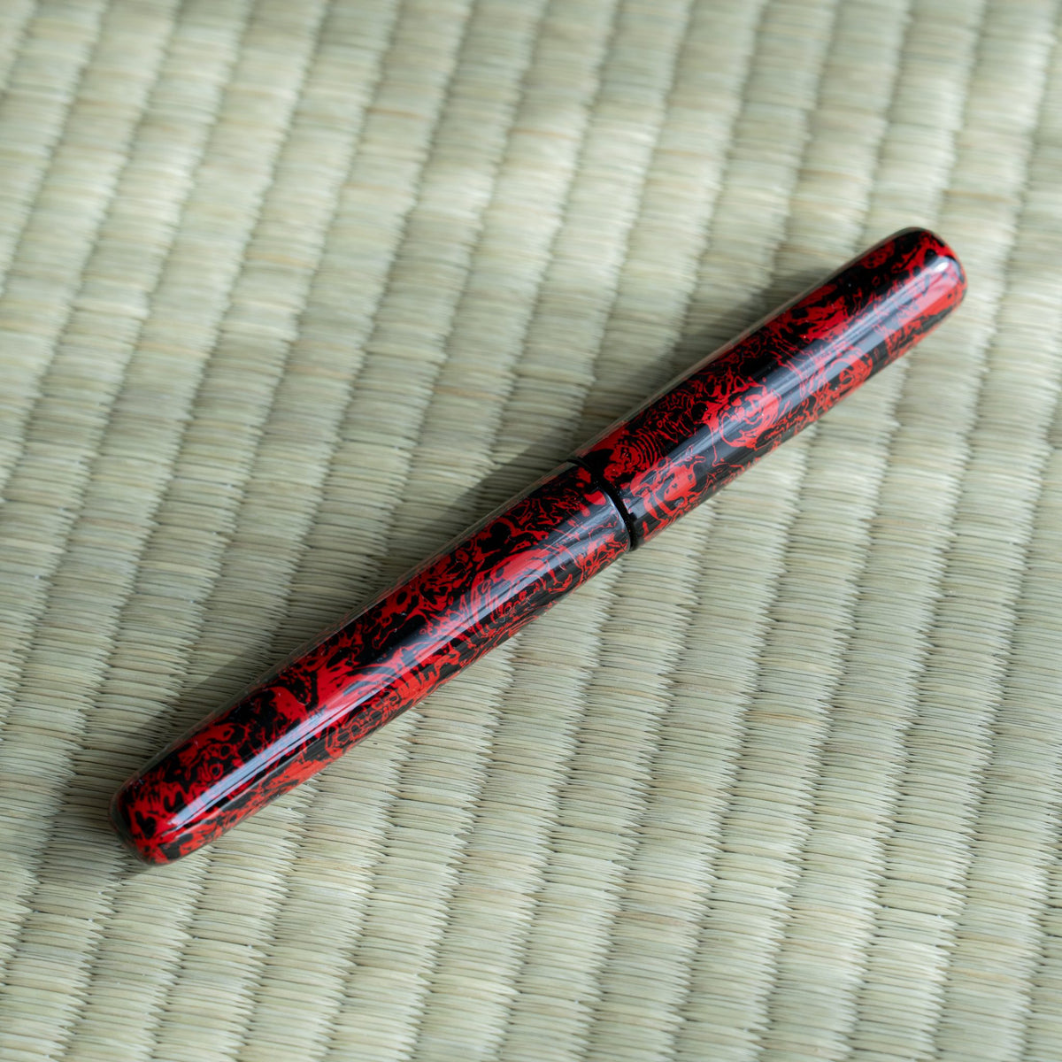 Capped Kagaribi Tsugaru-nuri fountain pen on tatami in soft light, mottled red and black urushi