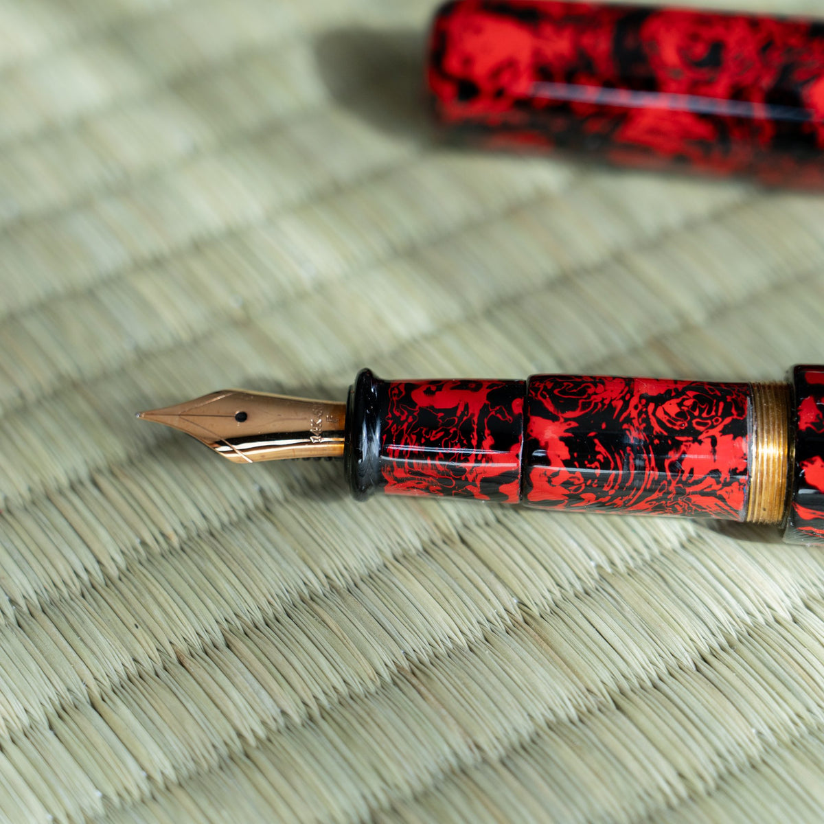 Side view of the Kagaribi fountain pen nib and section, red and black lacquer with brass threads